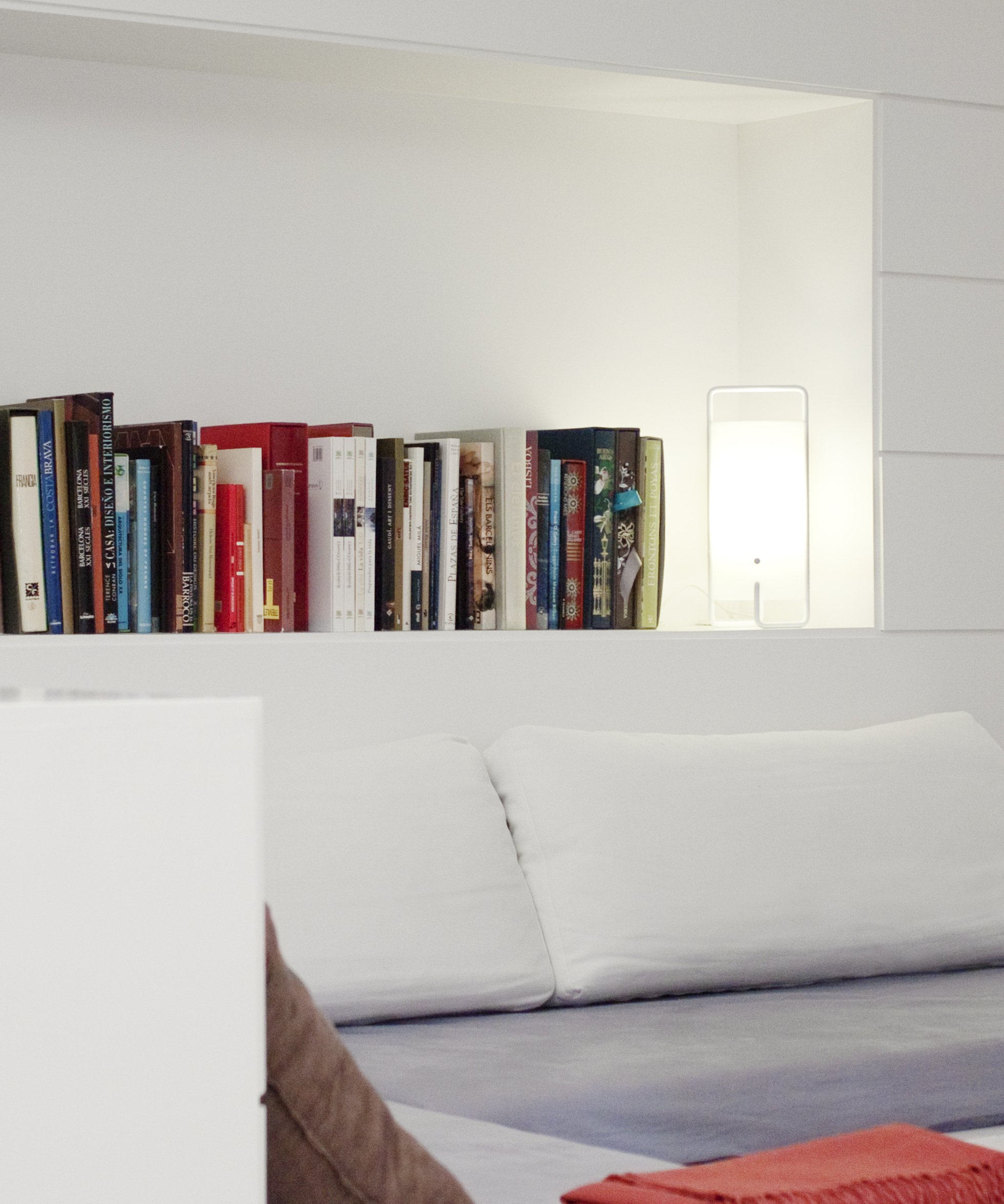 Weiße ASA Tischleuchte Santa & Cole neben Büchern in einem weißen Regal.