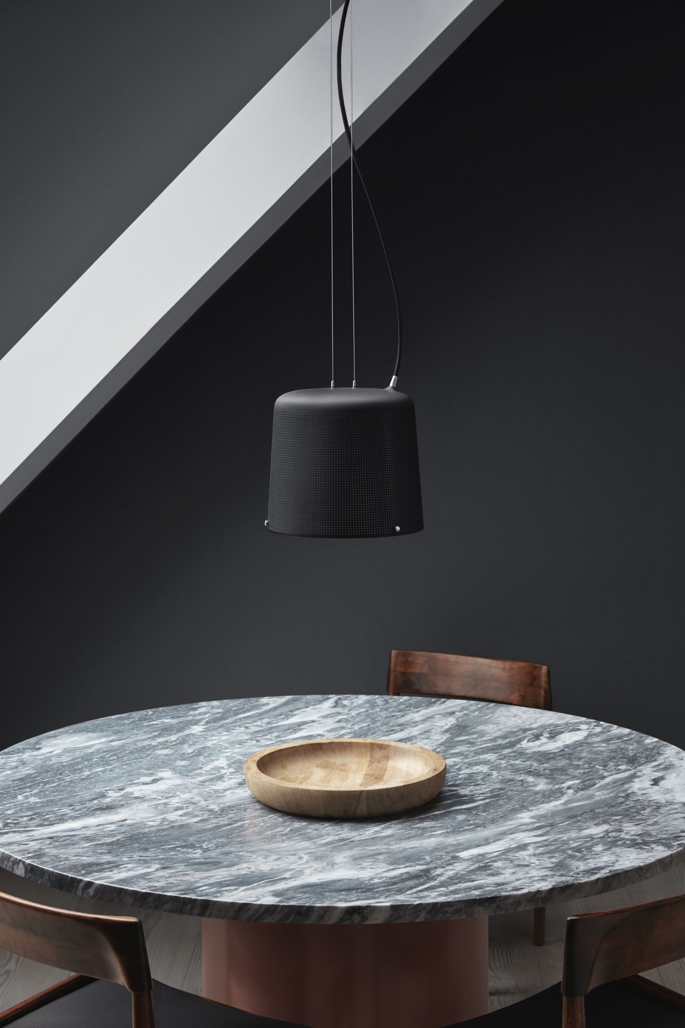 Schwarze Vipp Pendelleuchte über Marmortisch mit Holzschale, modernes Design für Esszimmer und Küche.