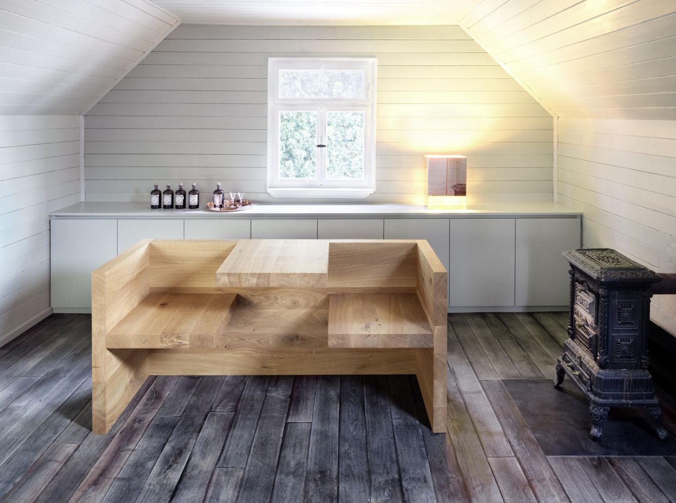 HP01 e15 Tischbank aus Holz im Raum mit Fenster und Ofen. Massivholzmöbel.