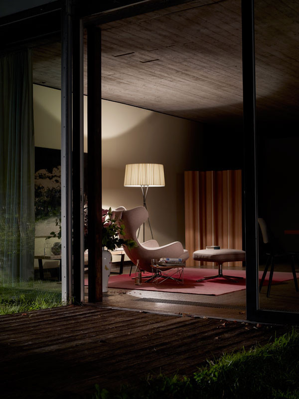 Vitra Sessel Grand Repos in rosa mit Hocker und Lampe im Wohnzimmer.