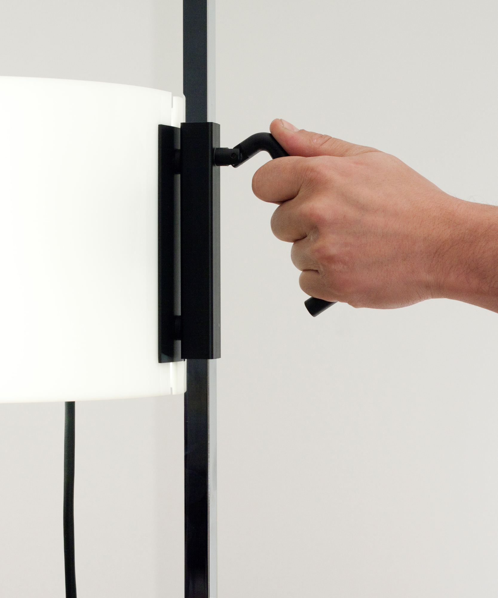 Detailaufnahme der Santa & Cole TMC Stehleuchte: Hand betätigt schwarzen Schalter, modernes Design.