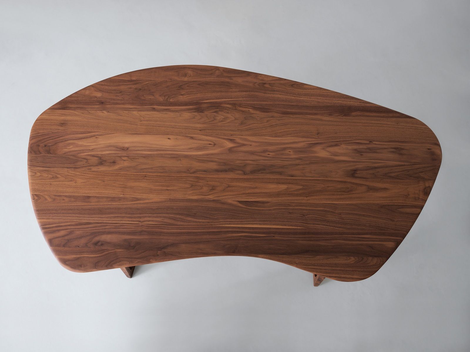 Draufsicht auf einen Twist Office Schreibtisch aus Nussbaumholz mit organischer Form und Holzstruktur.