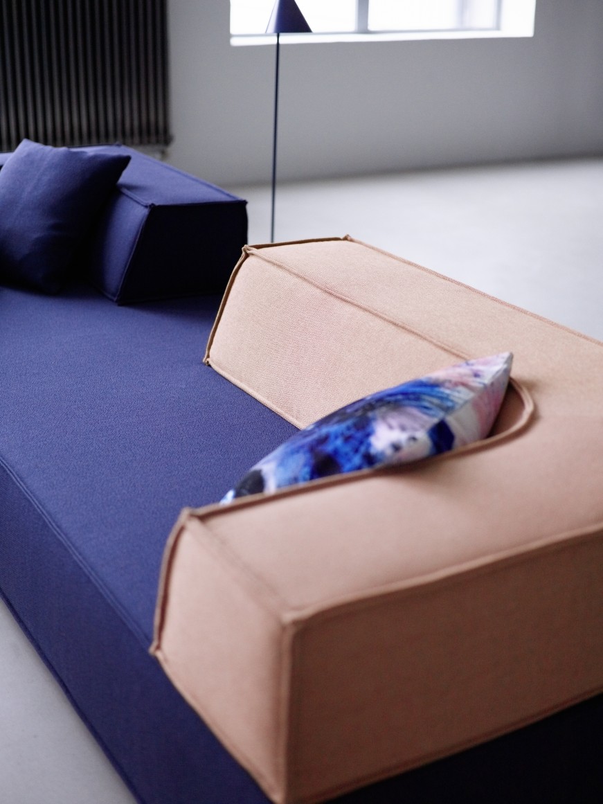 Nahaufnahme des modularen Cor Trio Sofas mit blauen Kissen und beigen Rückenelementen.