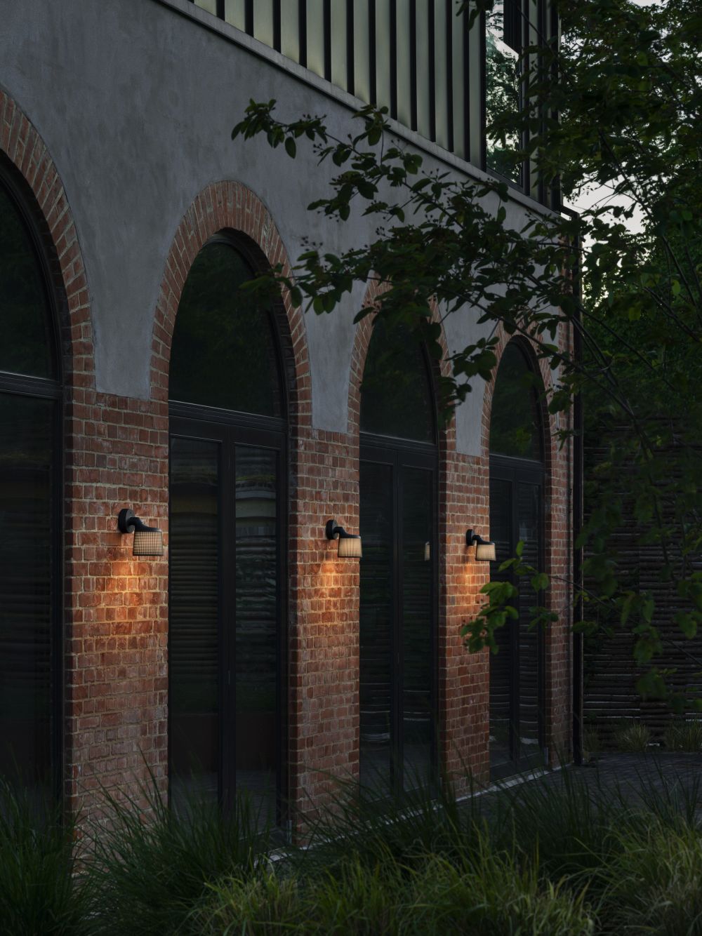 Drei Vipp Wandspots beleuchten eine Backsteinfassade mit hohen Fenstern. Außenleuchte für stilvolle Hausbeleuchtung.