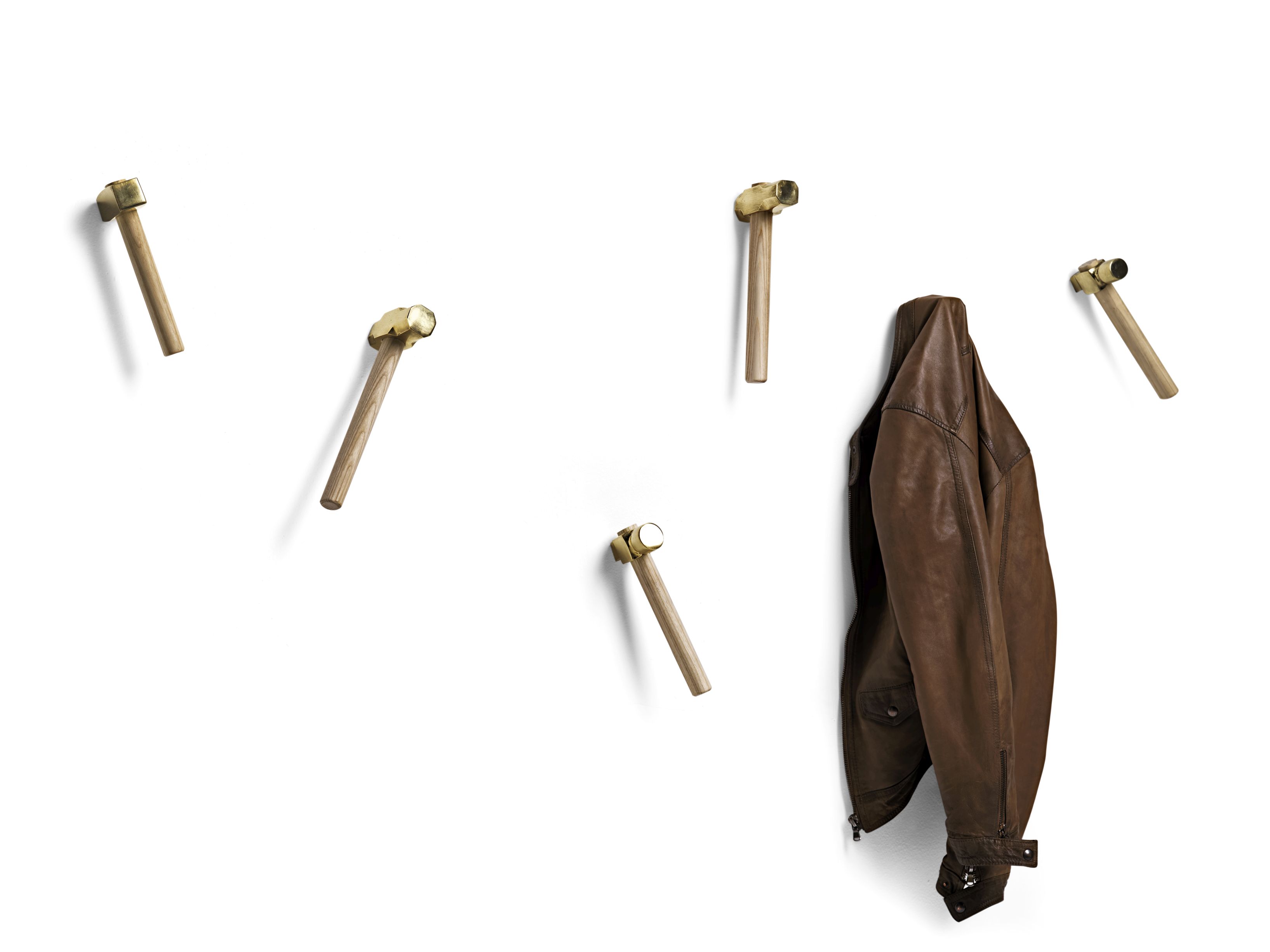 Bastaaa Kleiderhaken: Fünf Haken aus Holz und Messing an einer weißen Wand, eine Jacke hängt.
