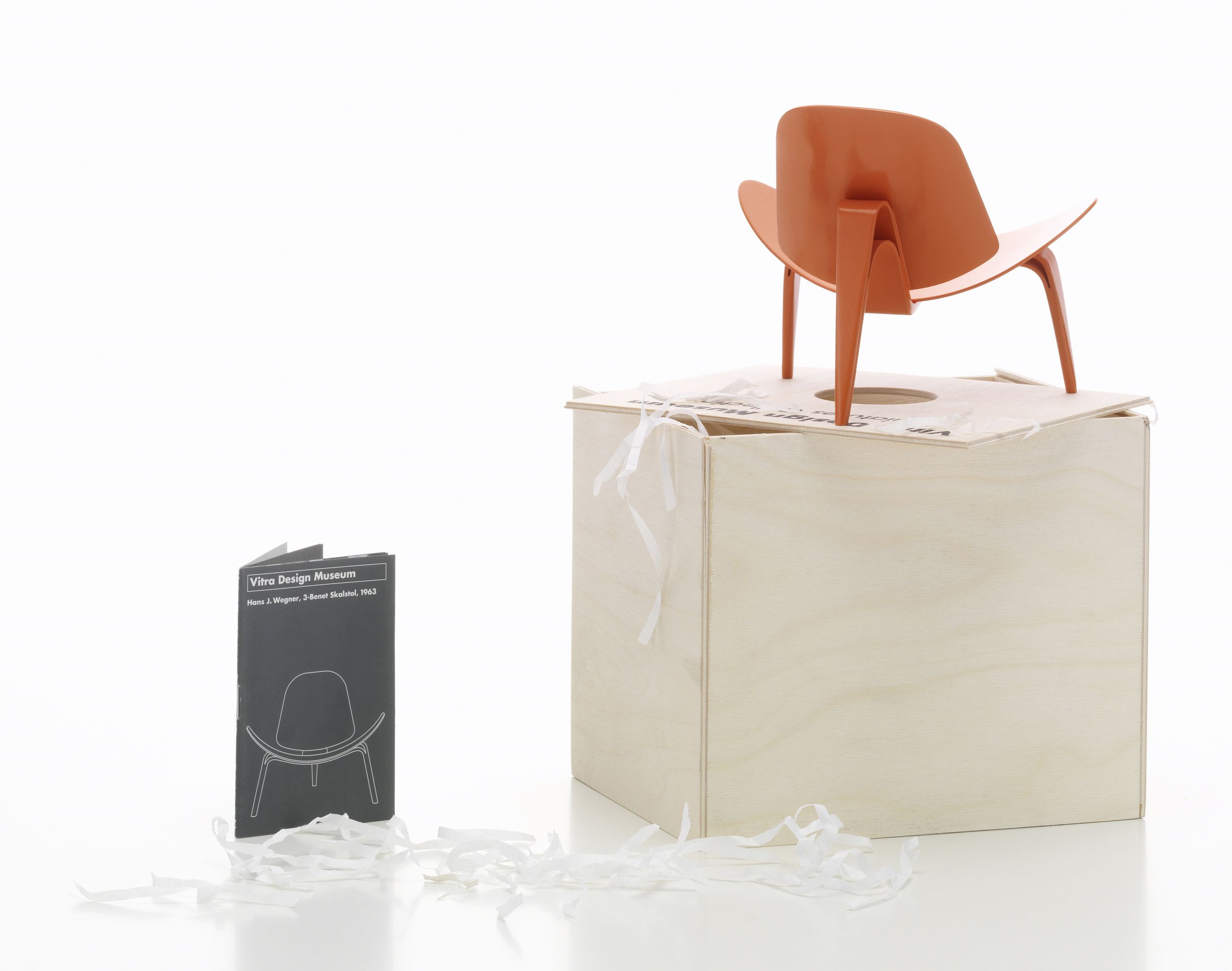 Orangefarbener 3-benet Skalstol Miniatur Stuhl von Vitra auf einem Holzwürfel, Designklassiker.