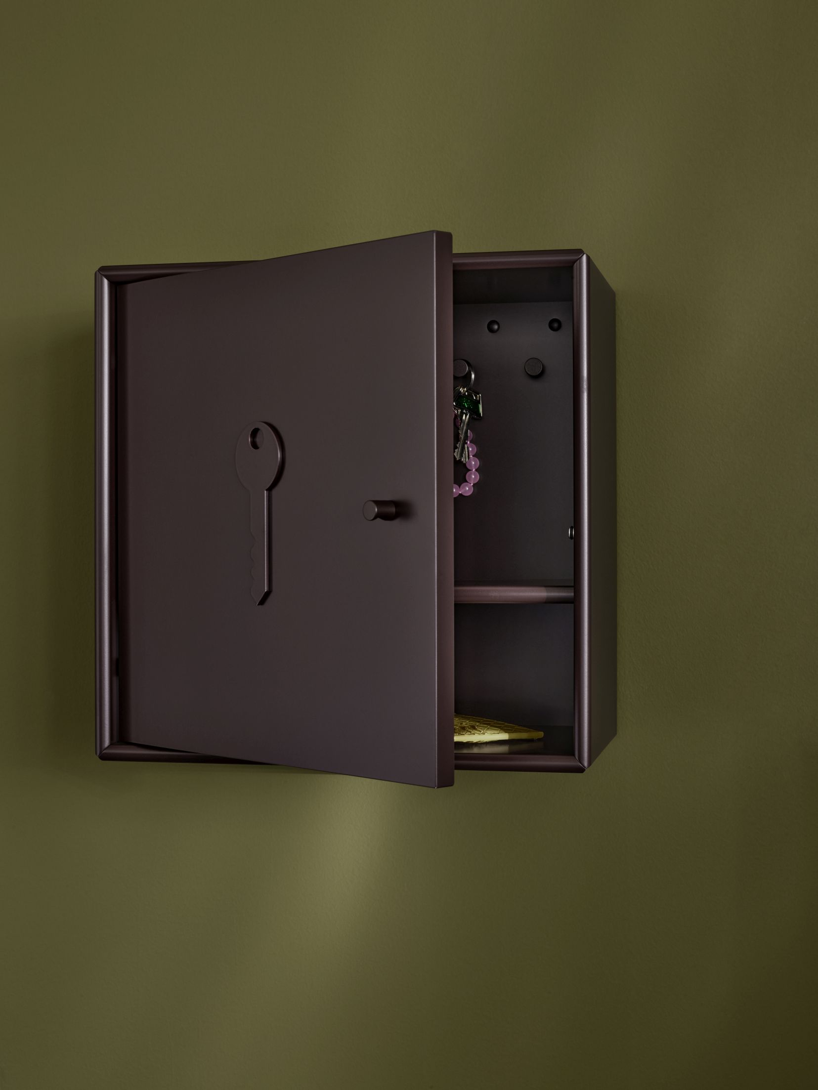 Unlock Schlüsselschrank Fennel Montana, braun, mit offener Tür an einer grünen Wand.