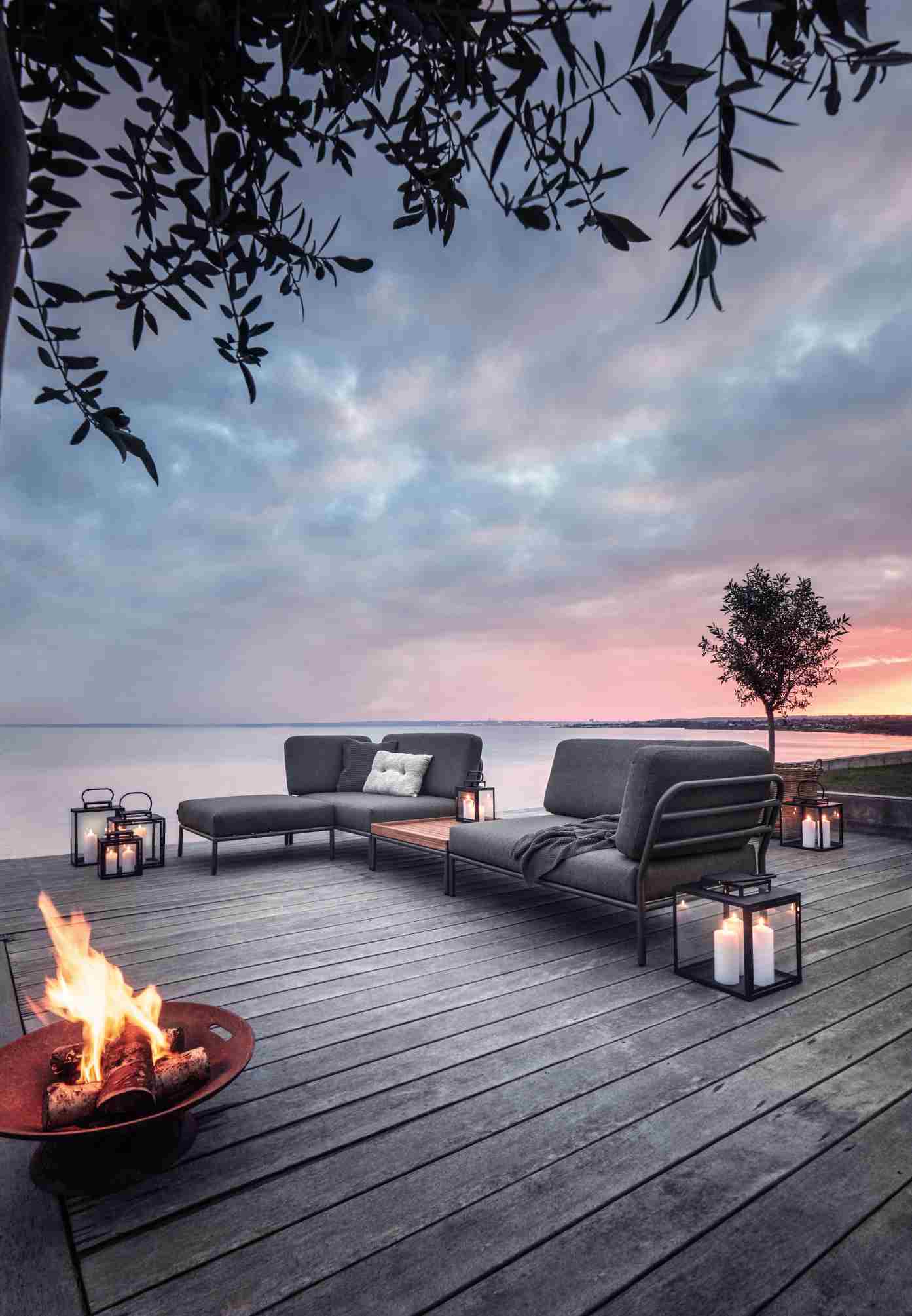 Level Couchtisch von Houe mit Outdoor Lounge Möbeln, Feuerkorb und Meerblick bei Sonnenuntergang.