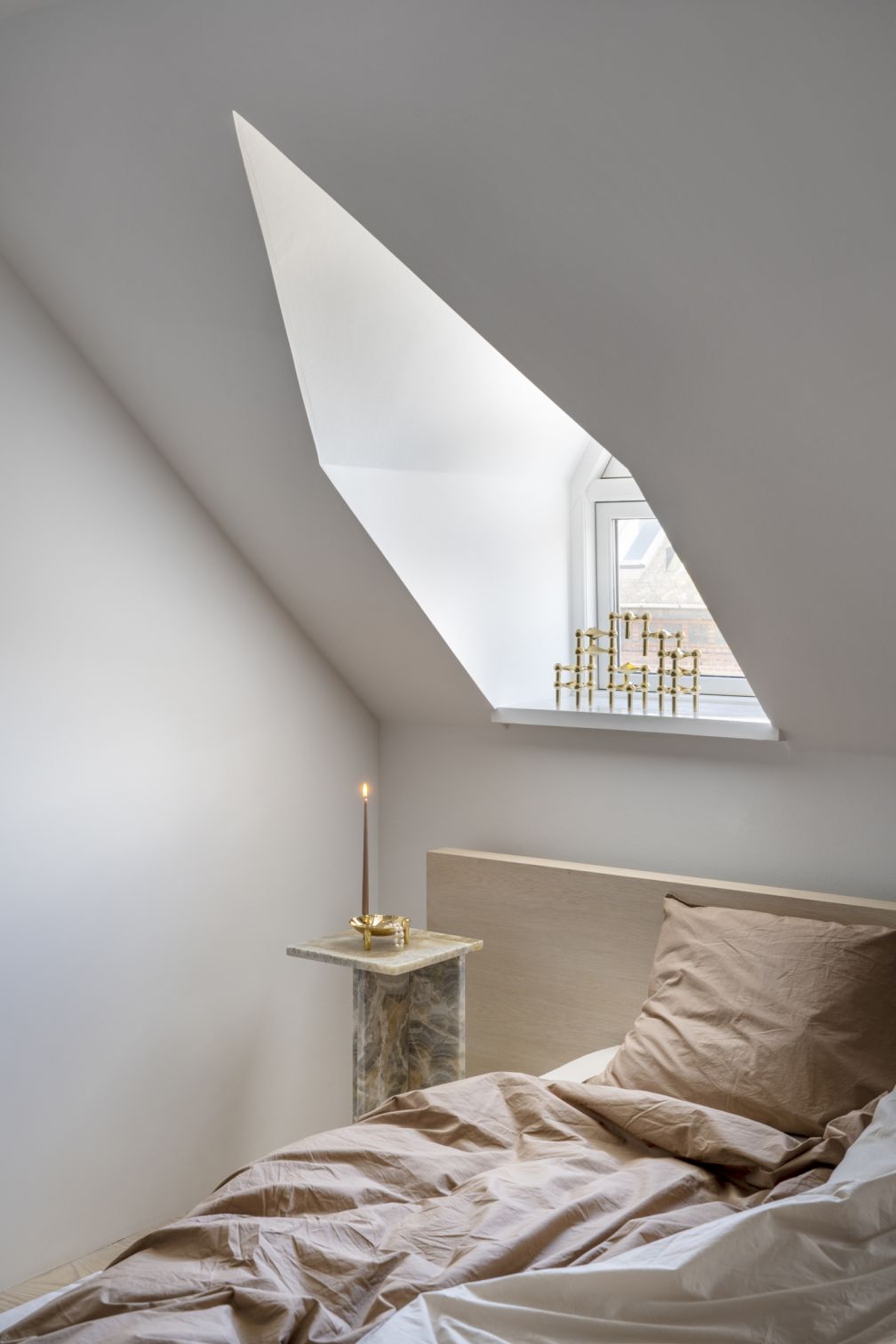 Schlafzimmer mit Kerzenständer aus Messing auf Nachttisch und Fensterbank, dekorative Wohnaccessoires.