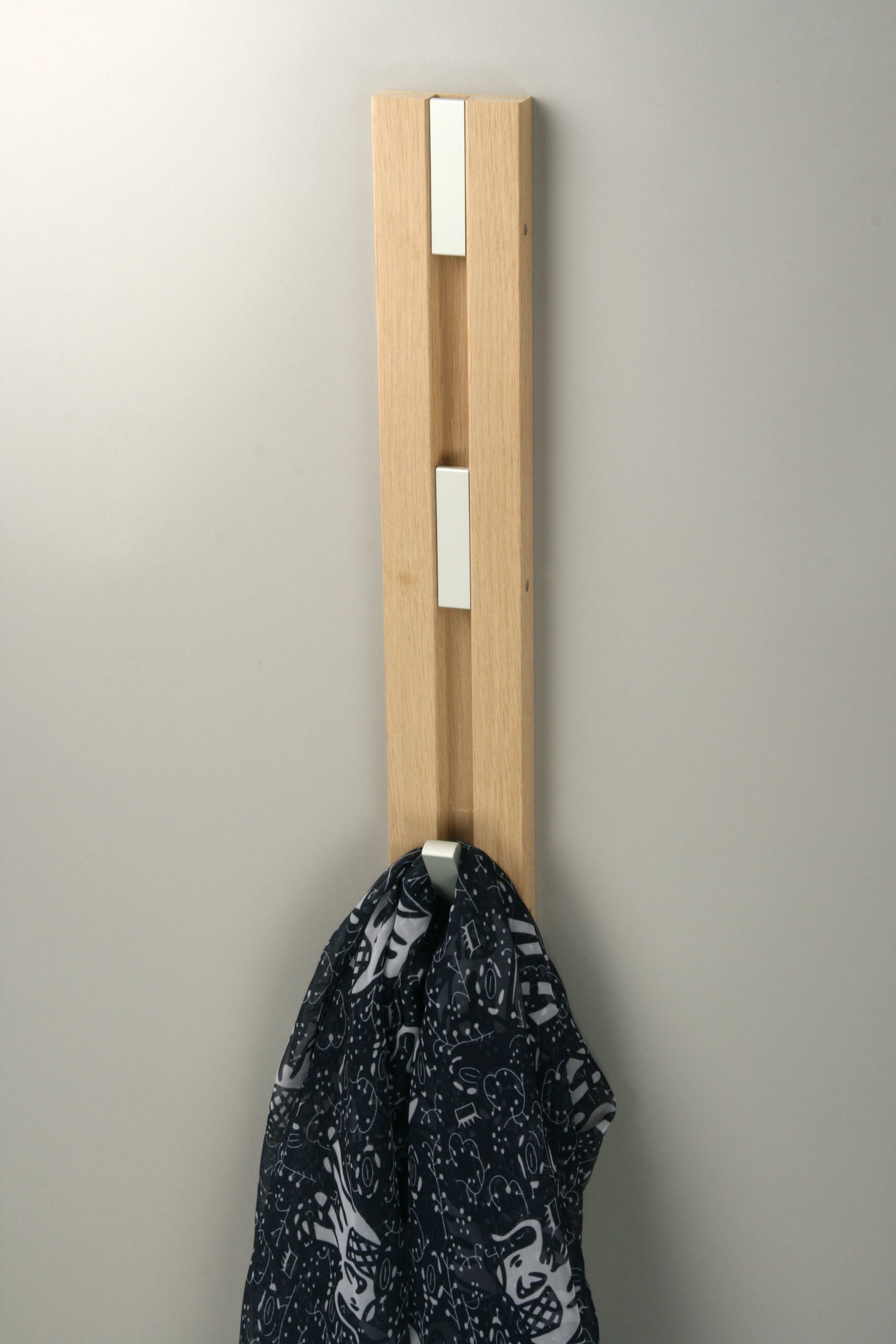Knax Wandgarderobe mit vier Haken aus hellem Holz, daran hängt ein Schal. Vertikale Garderobe.