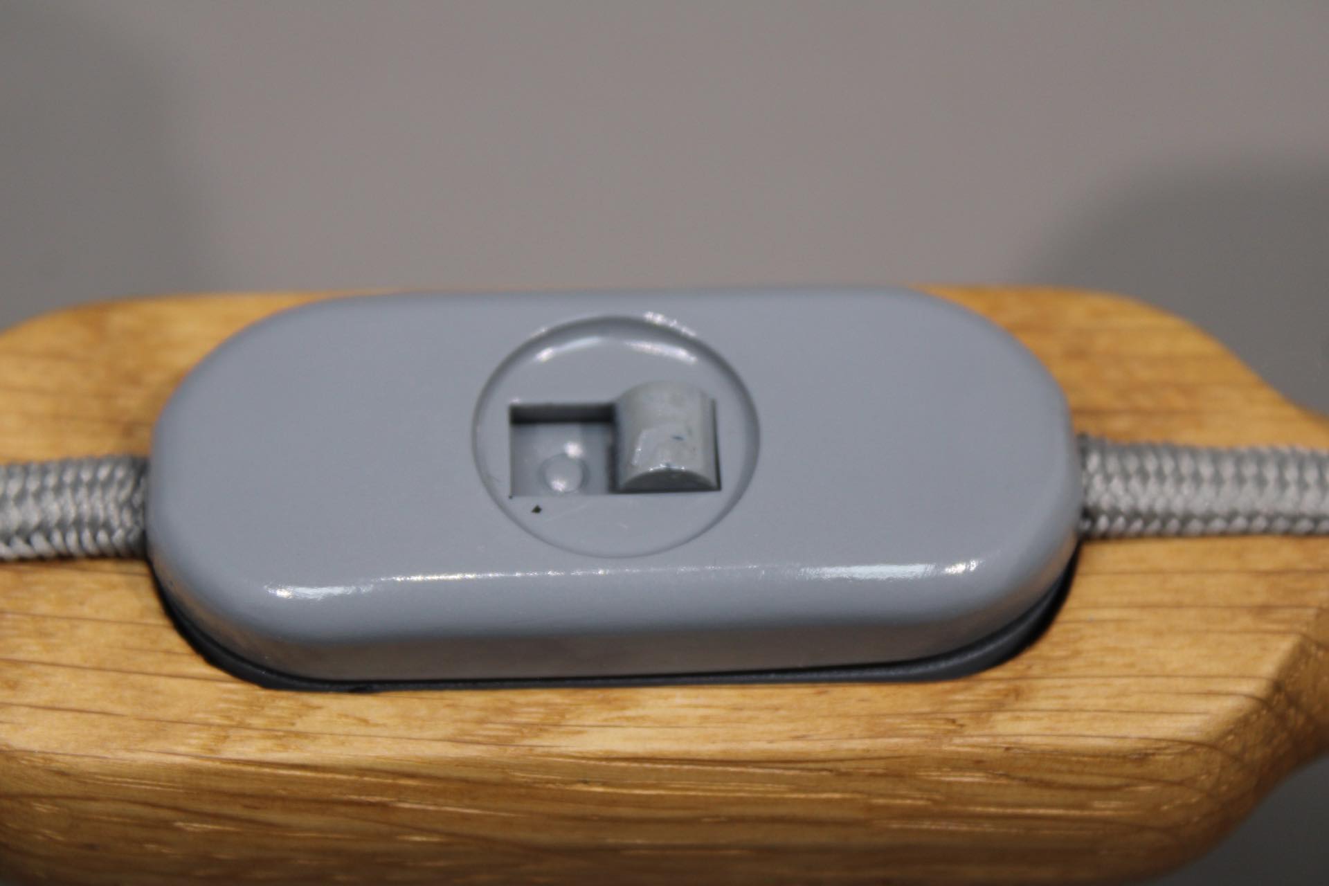 Detailaufnahme des Schalters der grauen Granny Tischleuchte mit Holzelementen.