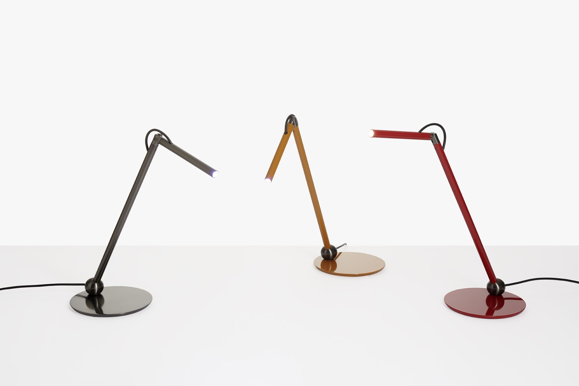 Drei Calamaio Tischleuchten von Oluce in Schwarz, Braun und Rot auf weißem Grund.