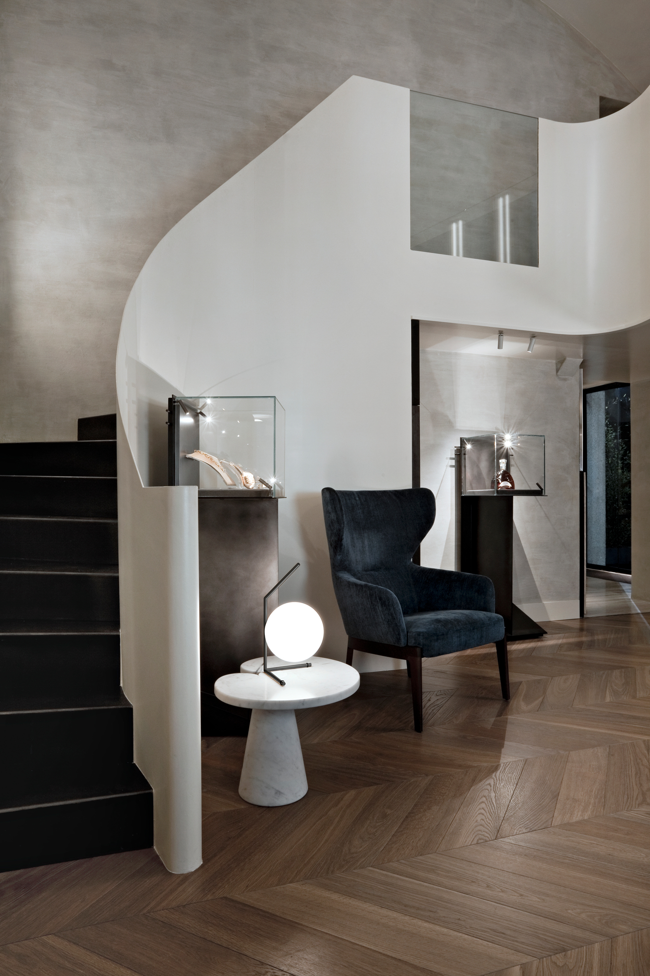 IC Lights T1 Low Tischleuchte von Flos auf Marmortisch neben Sessel und Treppe.