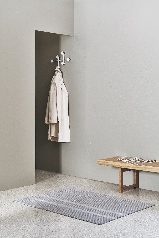 Graue Løype Fußmatte von Heymat im minimalistischen Flur mit Bank und Garderobe. Indoor/Outdoor Fußabtreter.