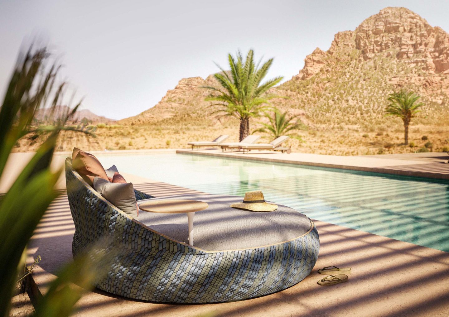 Dala Lounge Chair mit Polster von Dedon am Pool mit Wüstenlandschaft im Hintergrund.