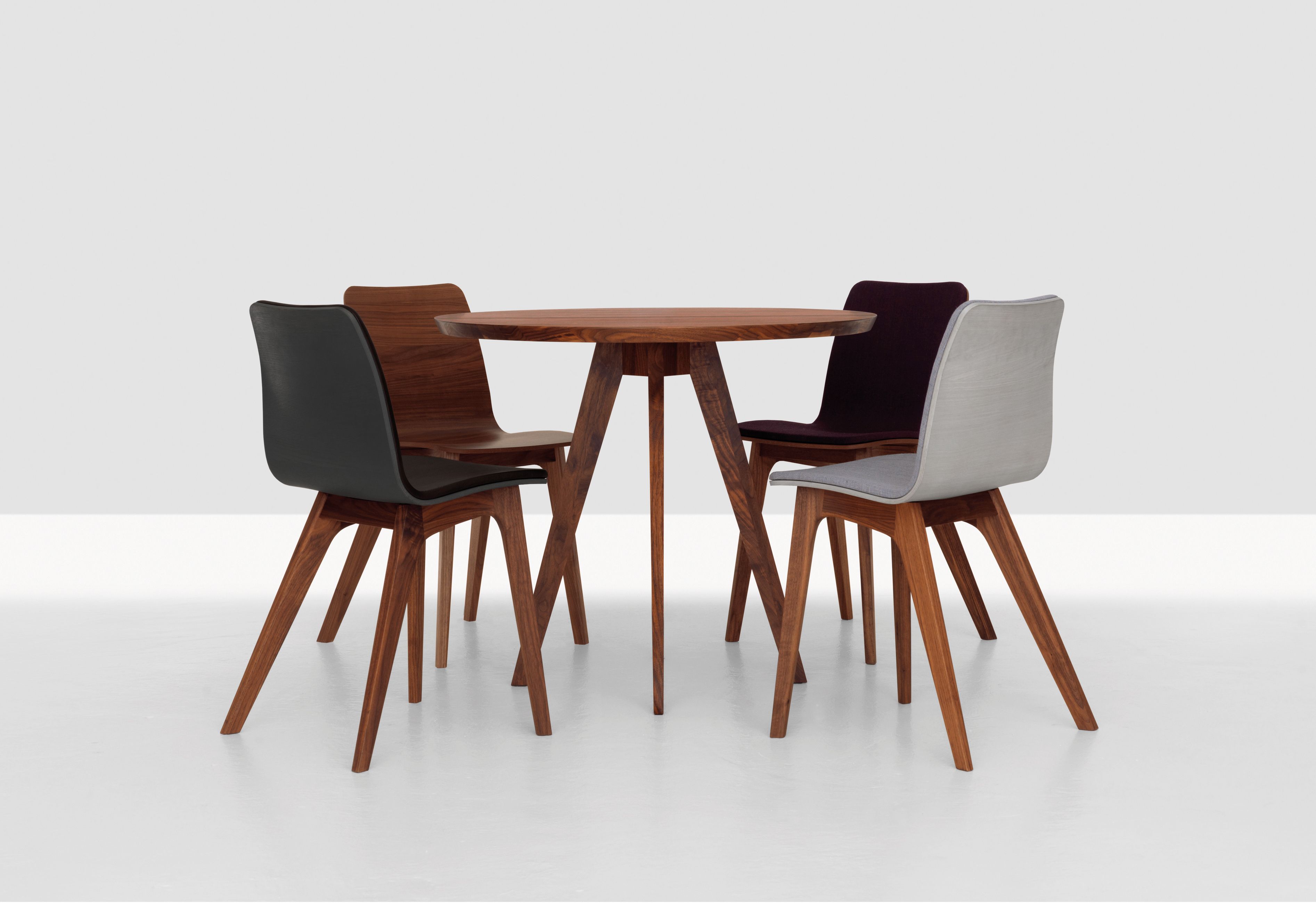 CENA Tisch: Runder Esstisch aus Holz mit vier Stühlen in verschiedenen Farben.