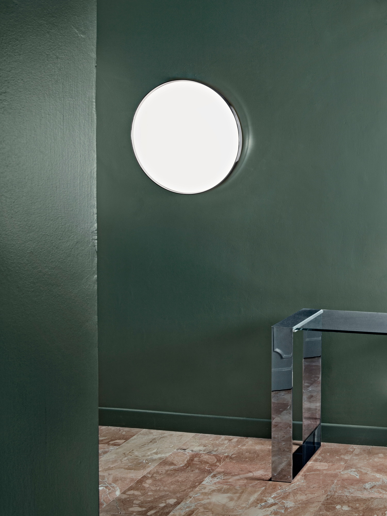 Clara Wandleuchte von Flos: Runde, transparente Deckenleuchte an grüner Wand. Modernes Design.