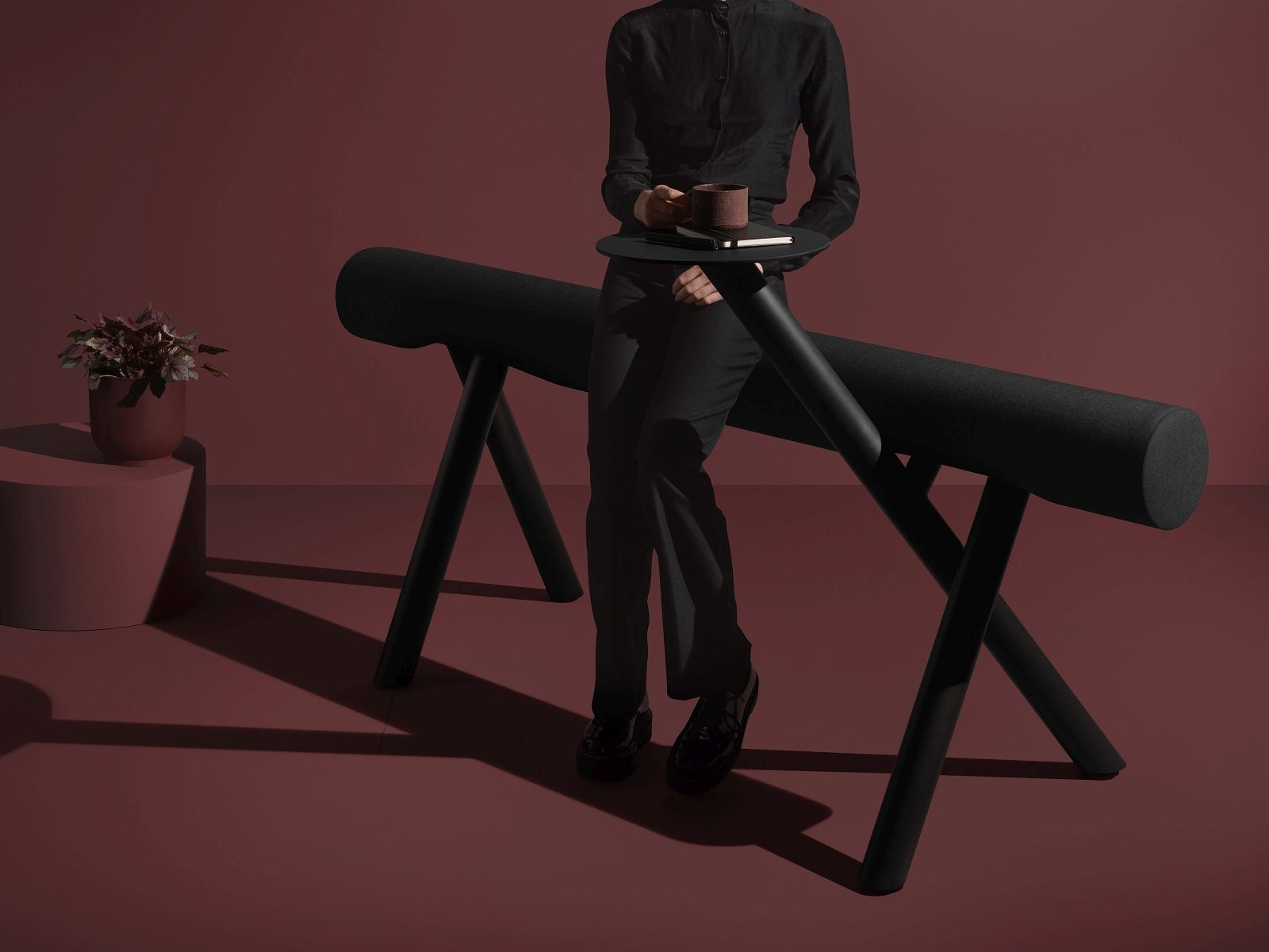 Schwarze Lumber Floor Sitzbank von Mizetto mit Person und Beistelltisch. Sitzmöbel für Büro.