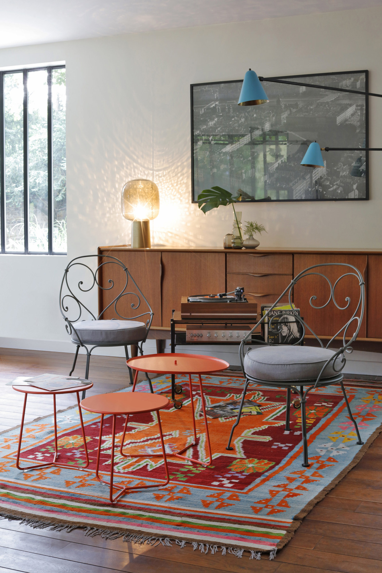 Nahaufnahme von drei kleinen, orangefarbenen Cocotte Beistelltischen von Fermob auf einem bunten Teppich.