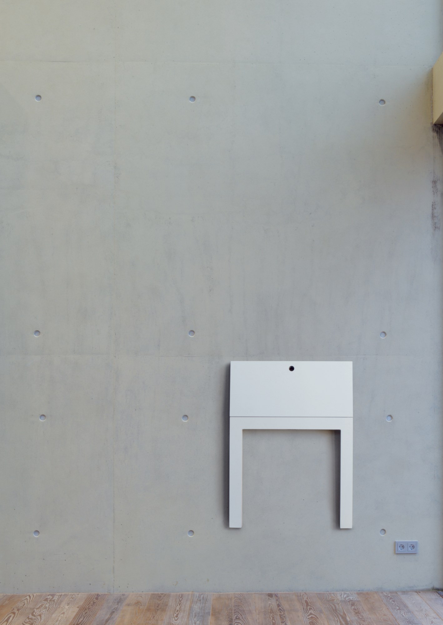 Weißer Last Minute Klapptisch von Nils Holger Moormann an einer Betonwand, platzsparend und minimalistisch.