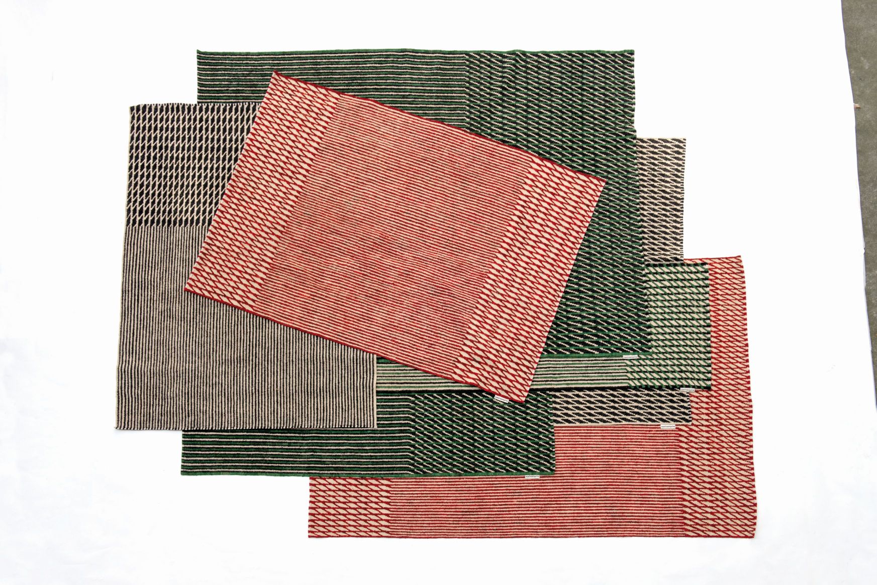 Mehrere farbige Läufer des Nanimarquina Blur Teppichs mit Streifenmuster überlappend auf weißem Hintergrund.