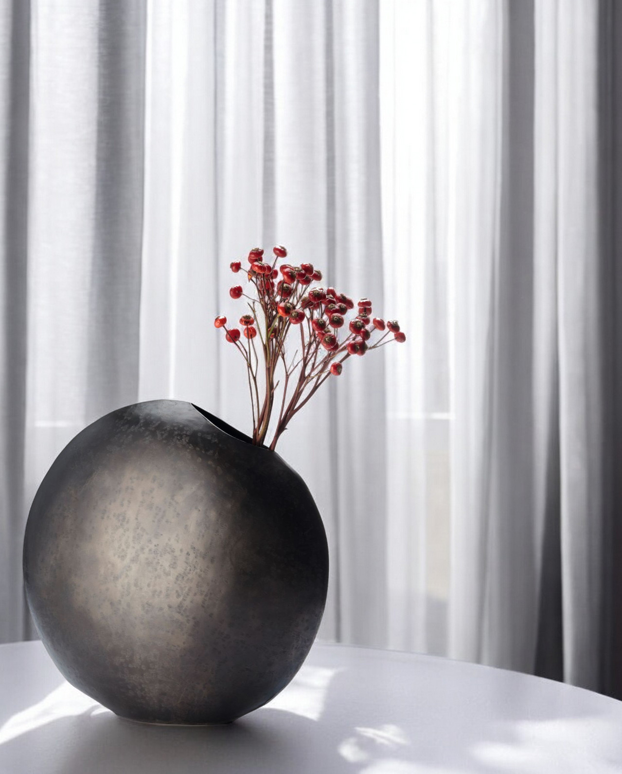 Monrovia Vase: Runde, dunkle Design-Vase mit roten Beeren-Zweigen als Dekoration. Einzigartiges Deko-Objekt.