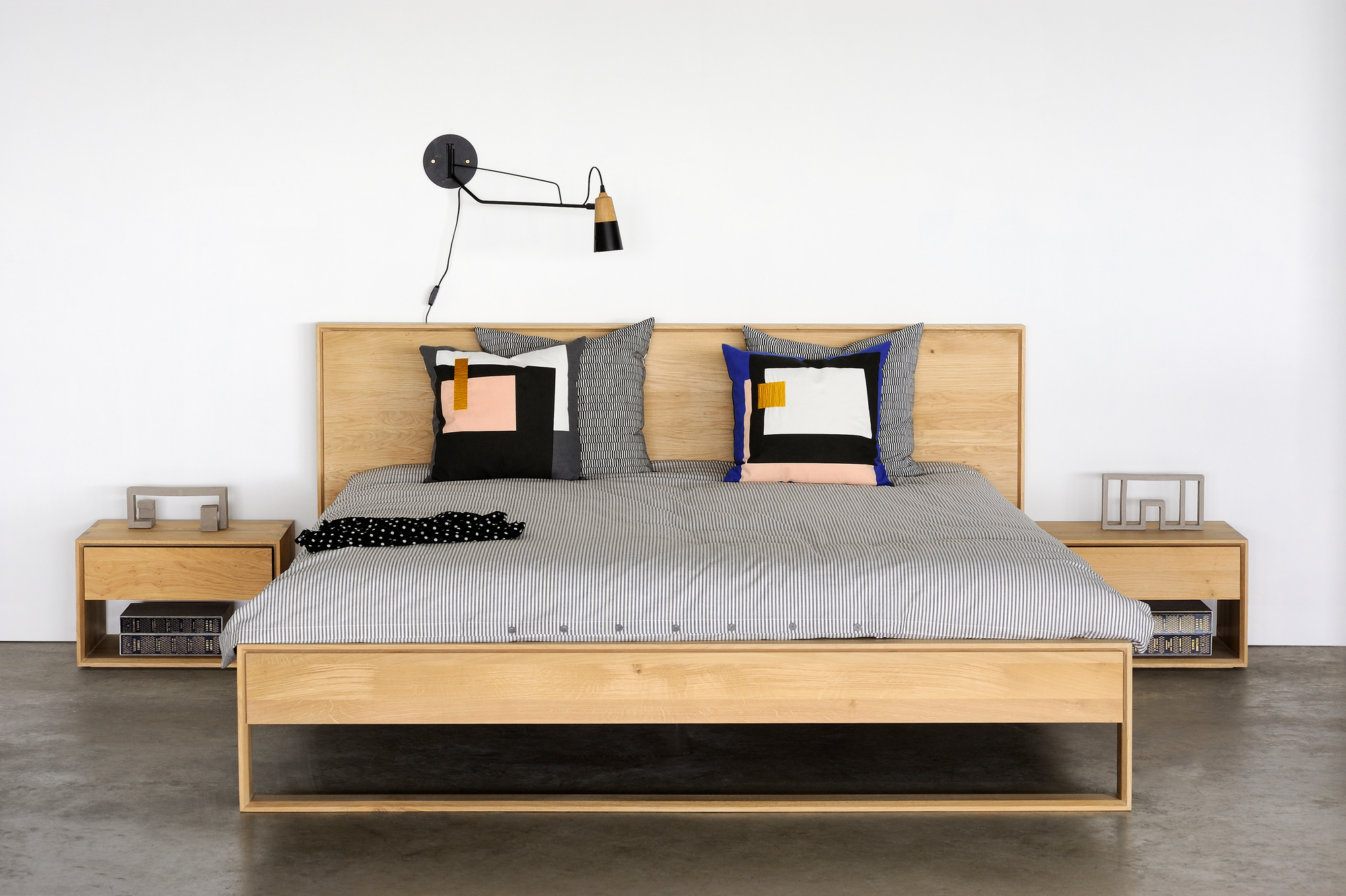 Nordic II Nachttisch von Ethnicraft aus Eiche neben einem Bett mit Nachttischlampe.