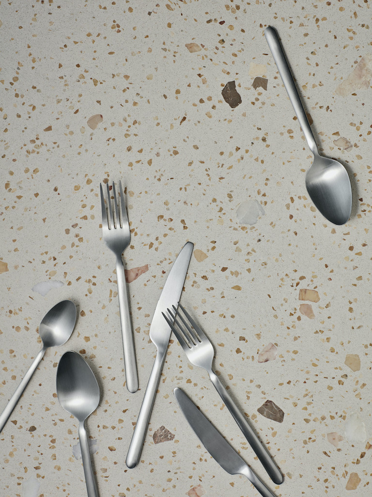 Stella Besteck-Set: Silbernes Besteck, Messer, Gabeln, Löffel auf gemustertem Untergrund. Hochwertiges, modernes Besteck für stilvolle Tischdekoration.