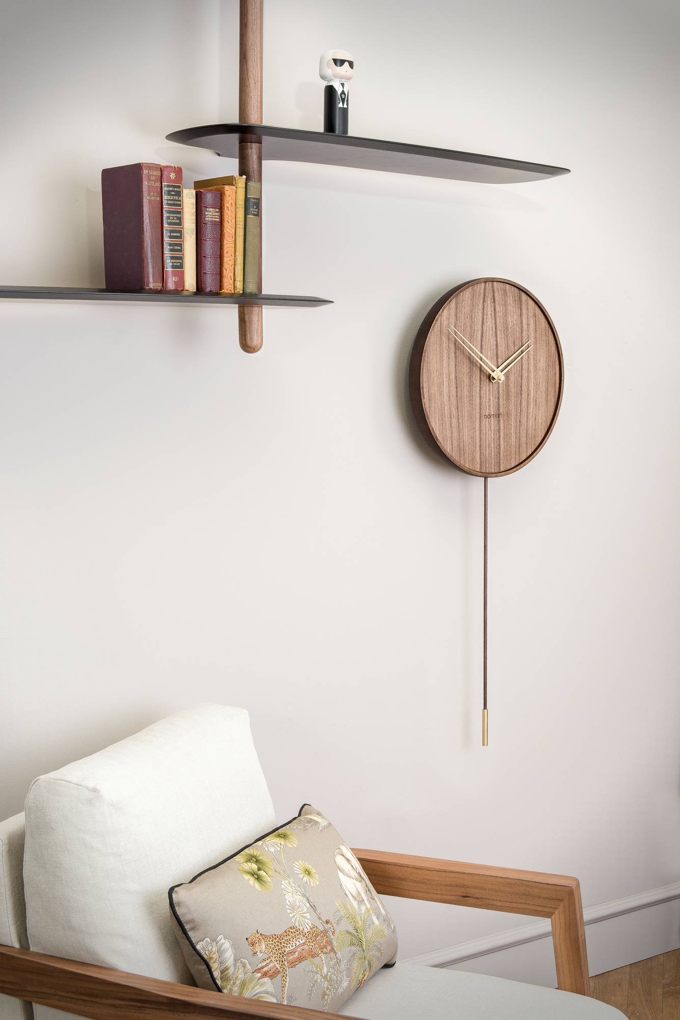Nahaufnahme der Nomon Swing Wanduhr aus Holz mit Pendel im modernen Wohnzimmer.