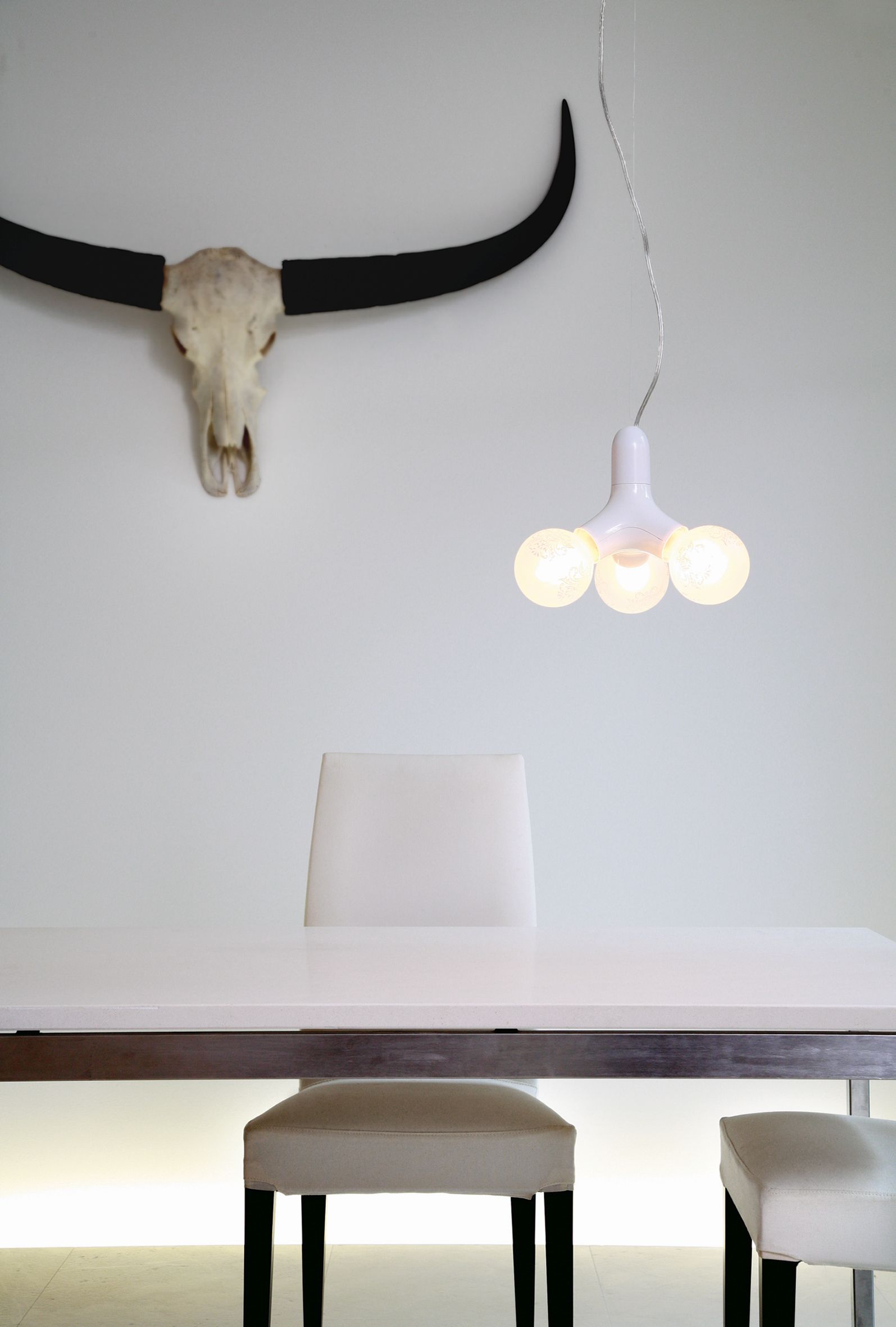 Moderne DNA Pendelleuchte mit drei Leuchten in Kupfer über Esstisch und Stühlen.