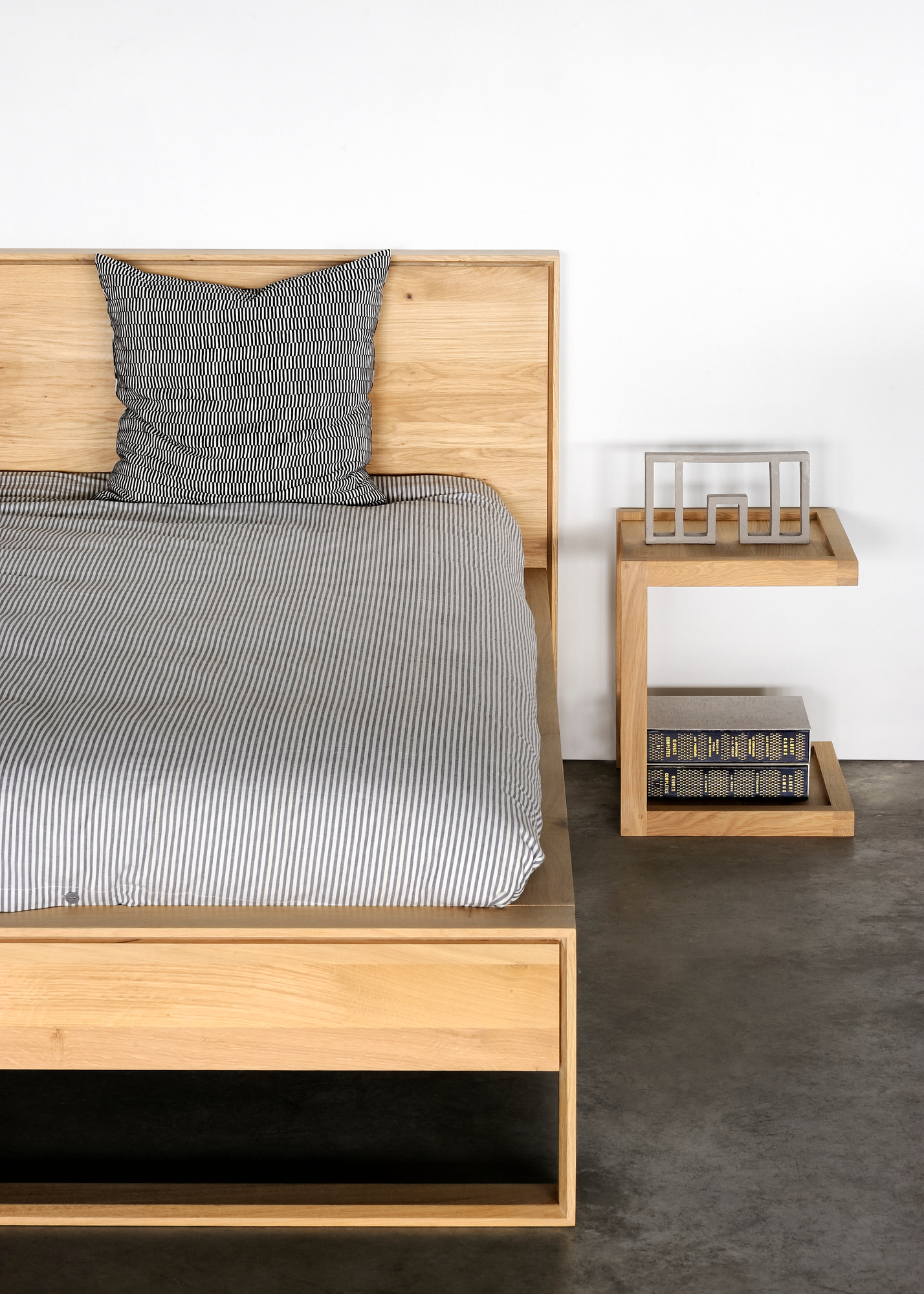 Nordic ll Bett aus Eiche von Ethnicraft mit Nachttisch und gestreifter Bettwäsche.