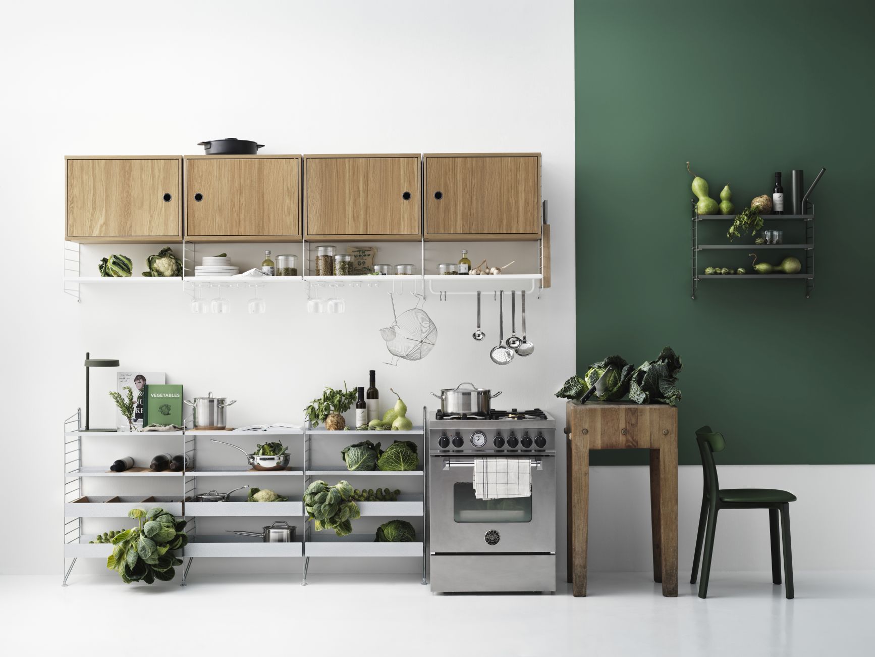 Küchenszene mit String Furniture Regalsystem und Schrankelement mit Schwenktür in Walnussoptik. Stauraum und Design für moderne Küchen.