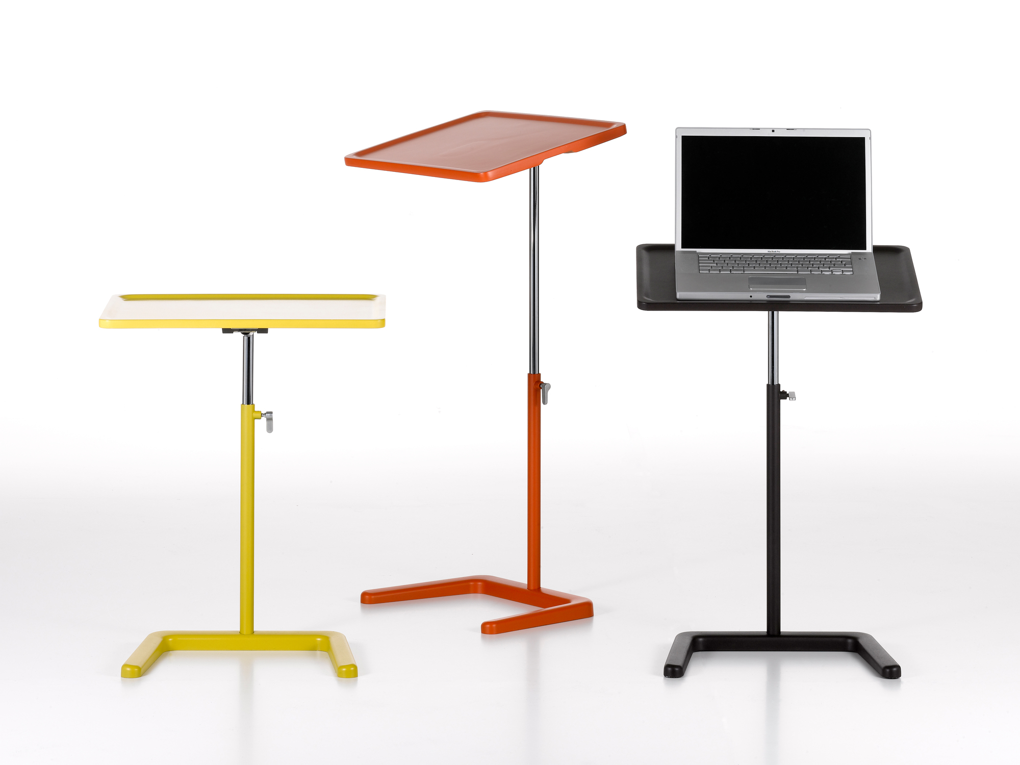 Drei farbige, höhenverstellbare Vitra Beistelltische, davon einer mit Laptop, freigestellt auf Weiß.