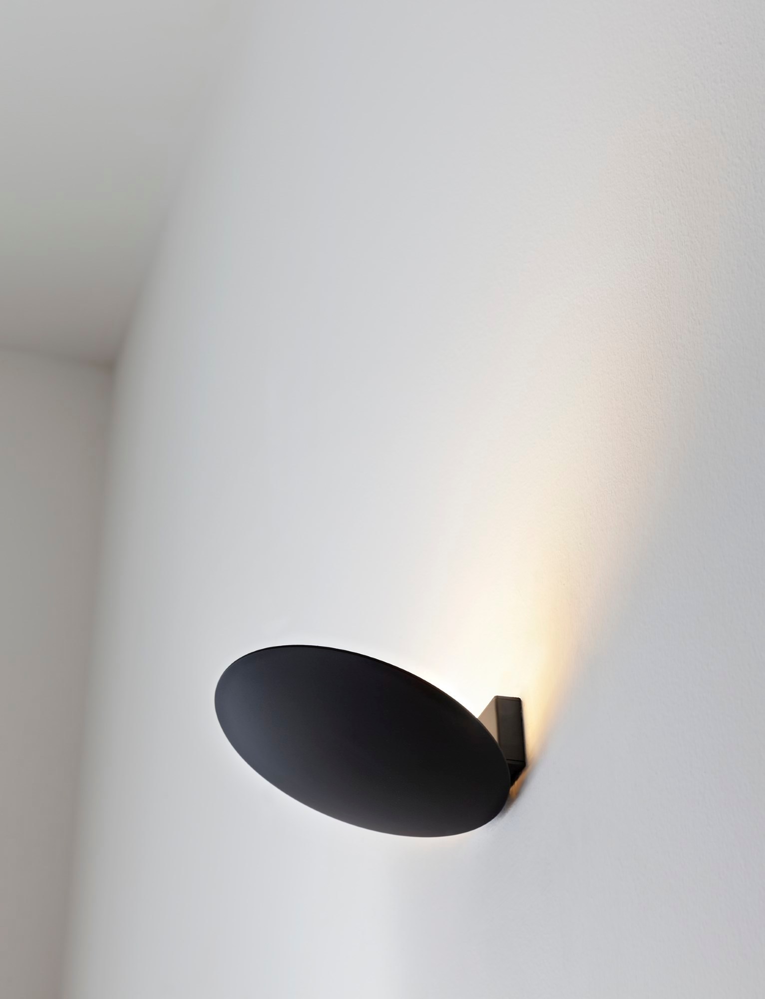 Schwarze Lederam WF Wandleuchte von Catellani & Smith an weißer Wand, indirekte Beleuchtung.