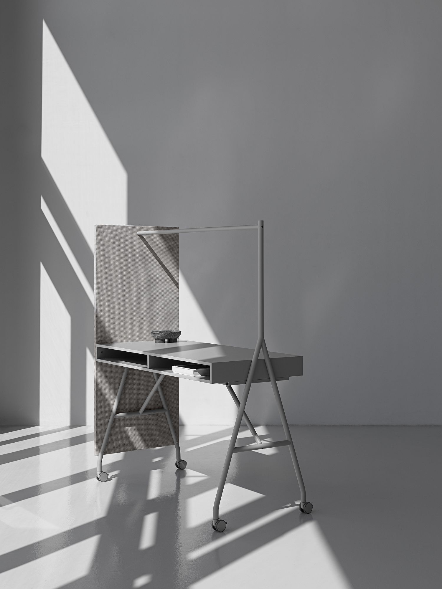 Grauer, minimalistischer Schreibtisch mit Rollen, Sichtschutz und Ablagefächern für Büro oder Homeoffice.