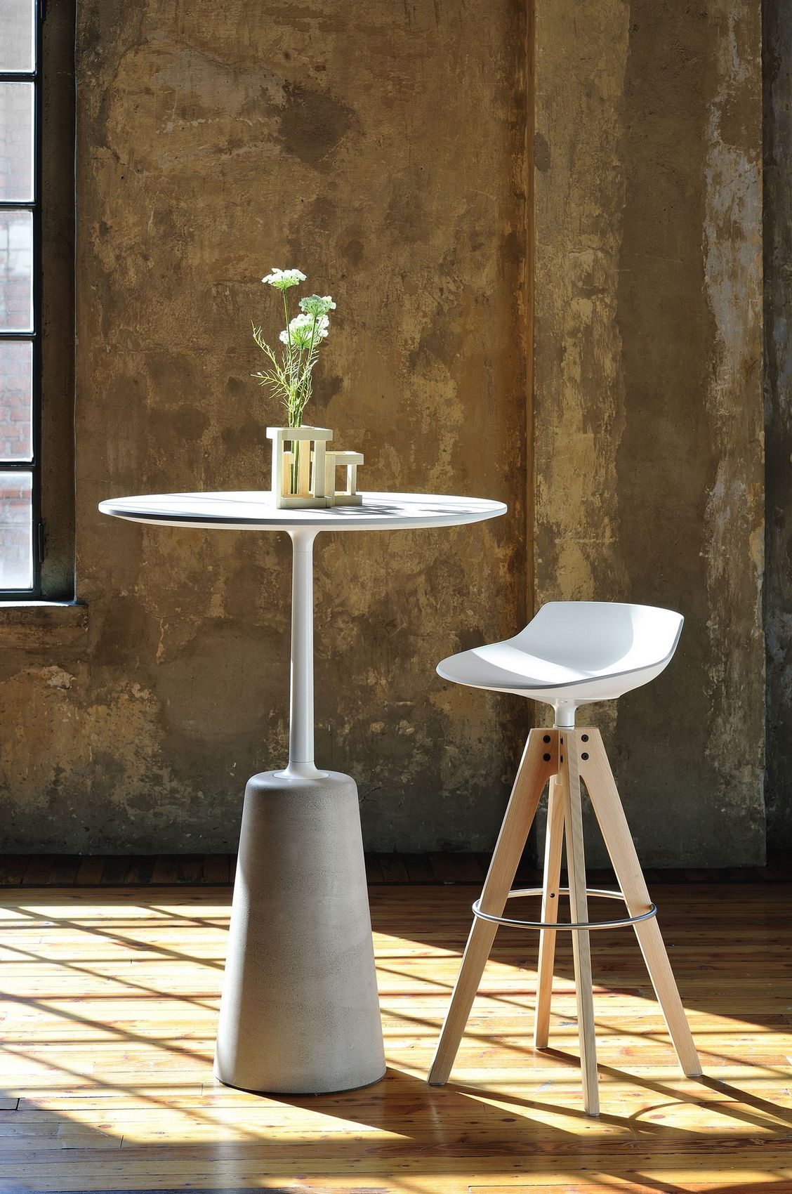 Flow Stool VN Hocker von MDF Italia neben Stehtisch mit Blumen auf Holzboden.