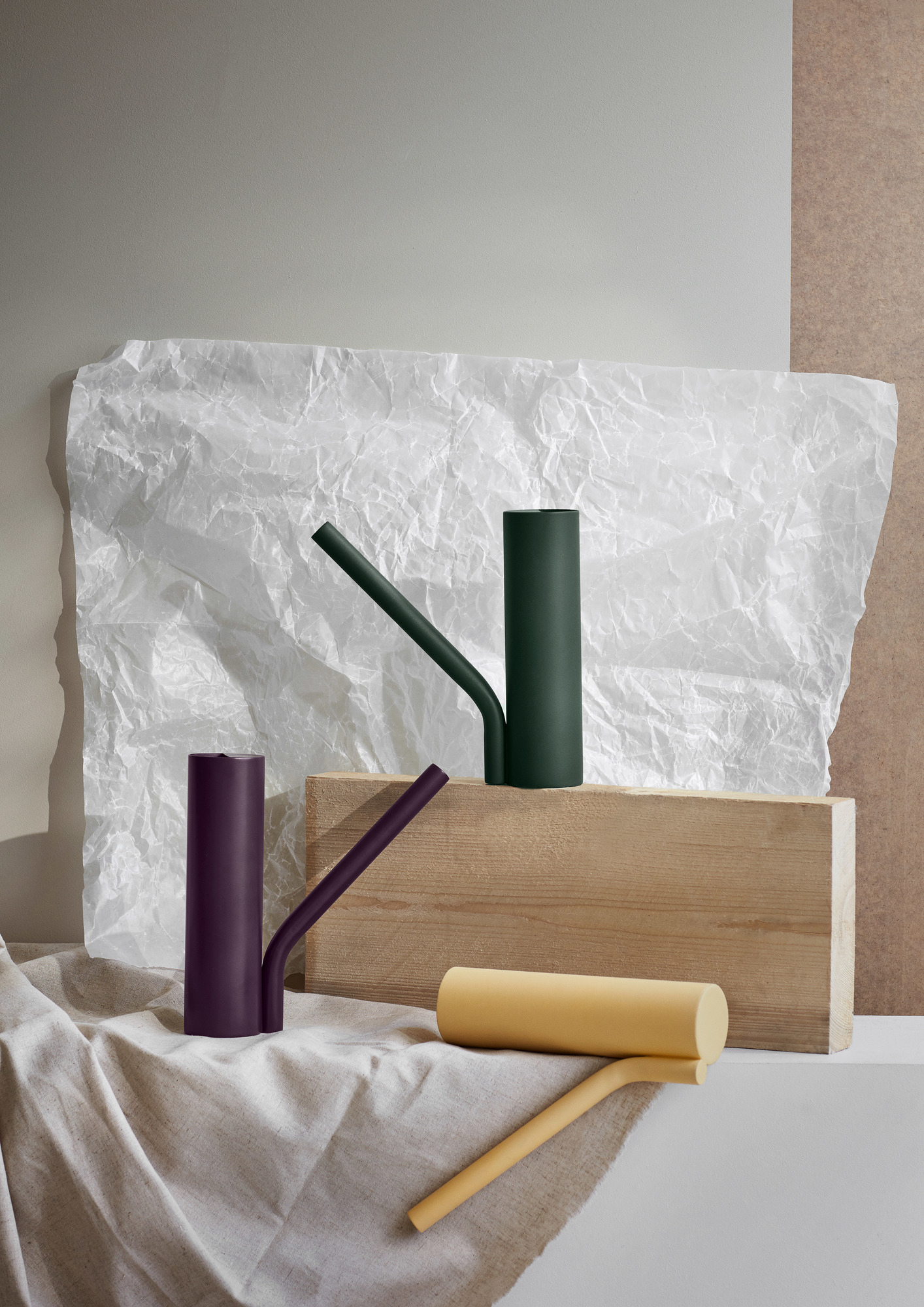 Produktfoto: Moderne Grab-Giesskanne in Grün, Lila und Gelb auf Holzblock und Stoff.