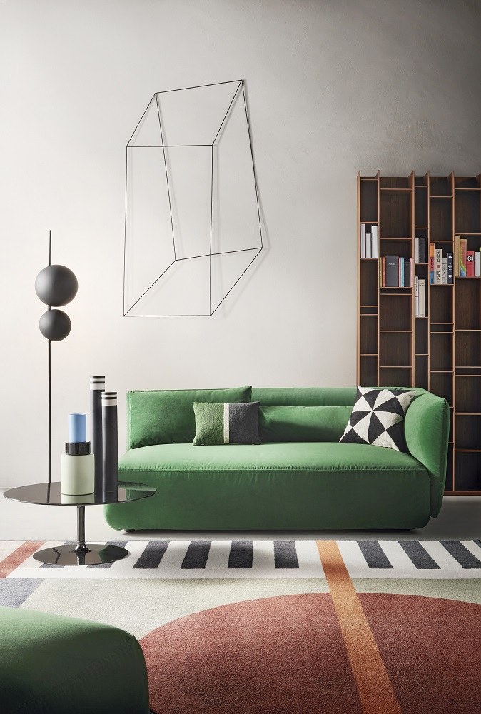 Modernes Wohnzimmer mit grünem Sofa und Random Wood Bücherregal von MDF Italia im Hintergrund.
