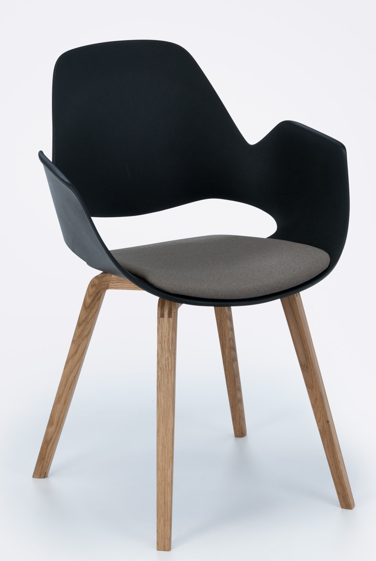 Falk Stuhl mit Armlehne von Houe, schwarze Sitzschale, graues Kissen und Eichenholzbeine.