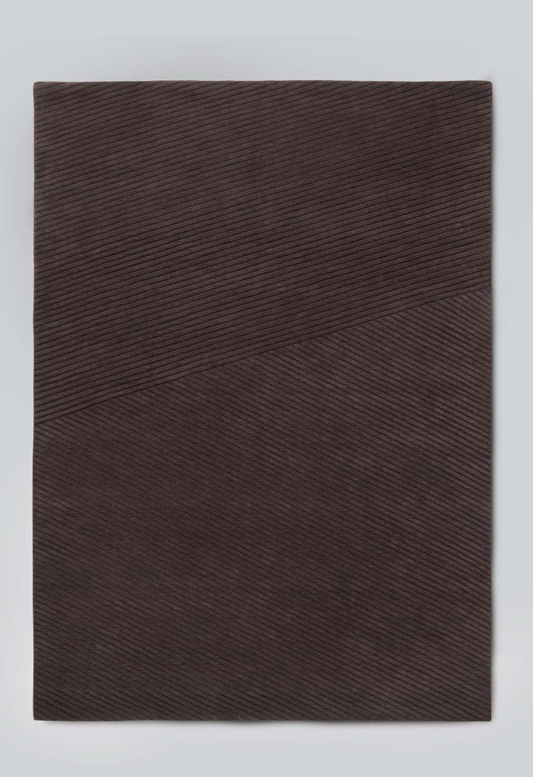 Nahaufnahme des dunkelbraunen Row Teppichs von Northern mit feiner Rippenstruktur.