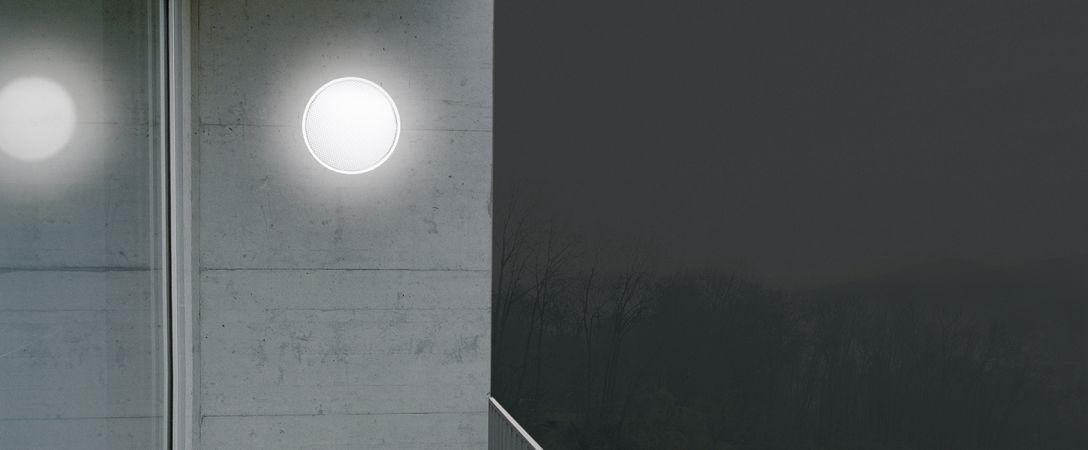 O-lite Wandleuchte: Runde Deckenleuchte mit warmweißem Licht an einer Betonwand. Innenbeleuchtung.