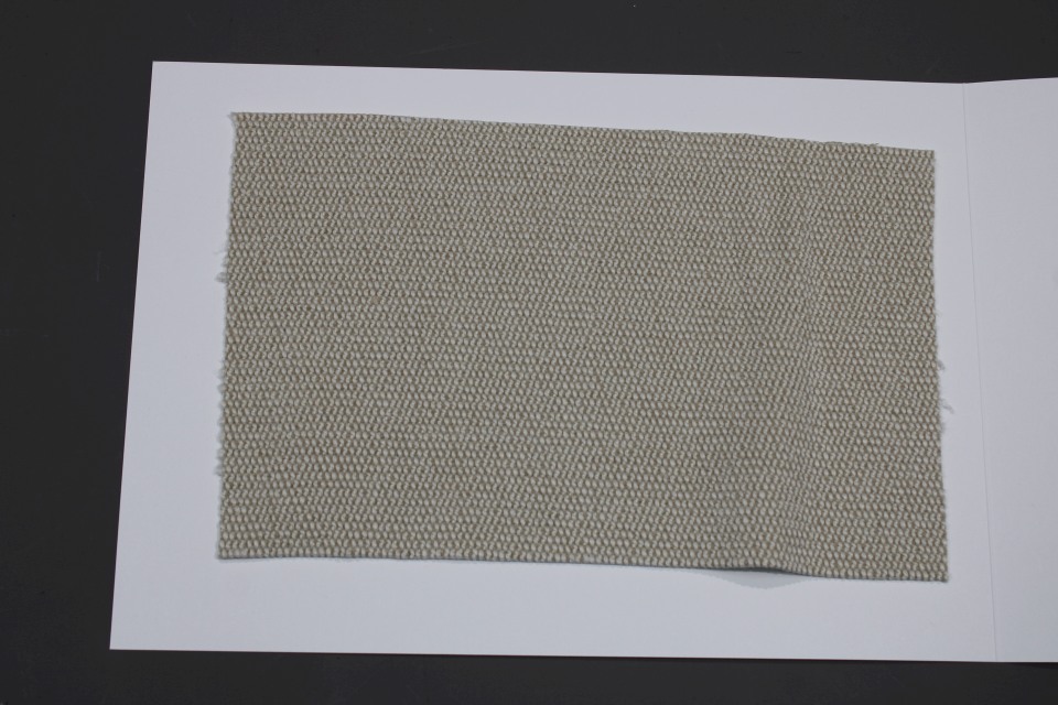 Stoffmusterkarte Gruppe 91 Cor: Nahaufnahme eines beigen, gewebten Textil-Musters für Möbelstoffe.