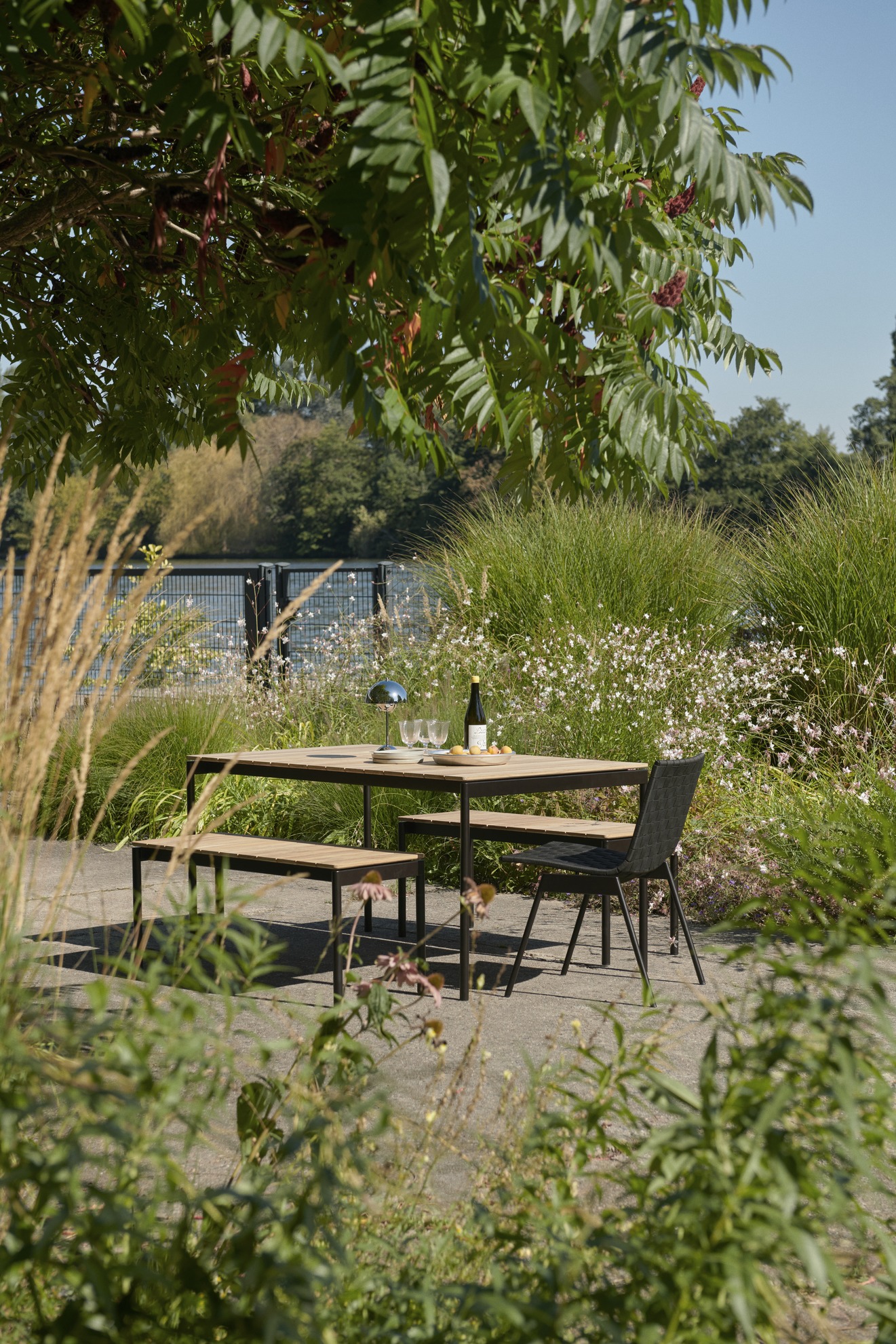 AndTradition Ville AV27 Outdoor Bankgruppe mit Tisch, Bank und Stuhl im Garten.