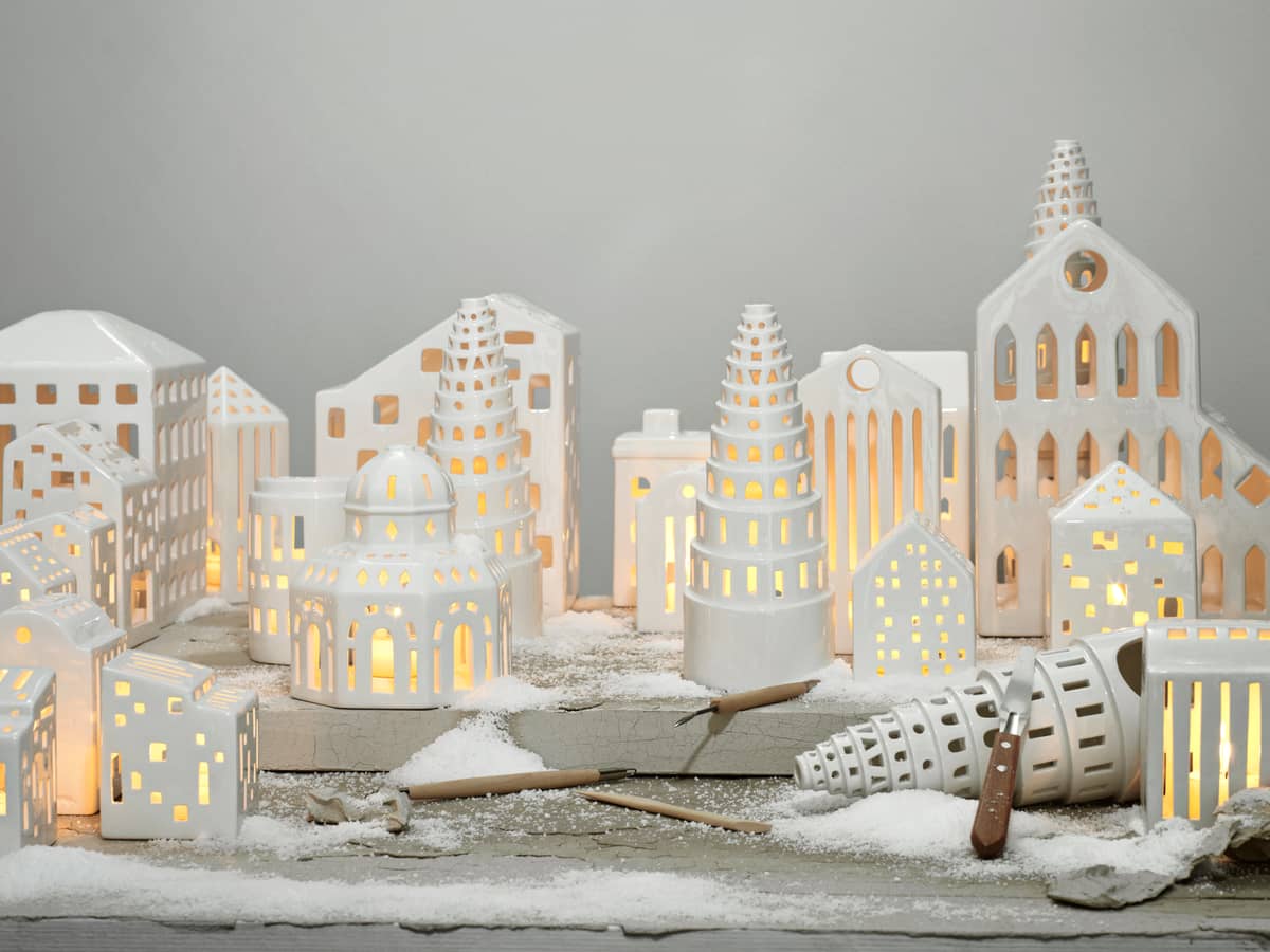 Detailaufnahme von Kähler Urbania Lichthäusern, die eine kleine Stadt aus weißer Keramik mit warmem Kerzenlicht bilden.