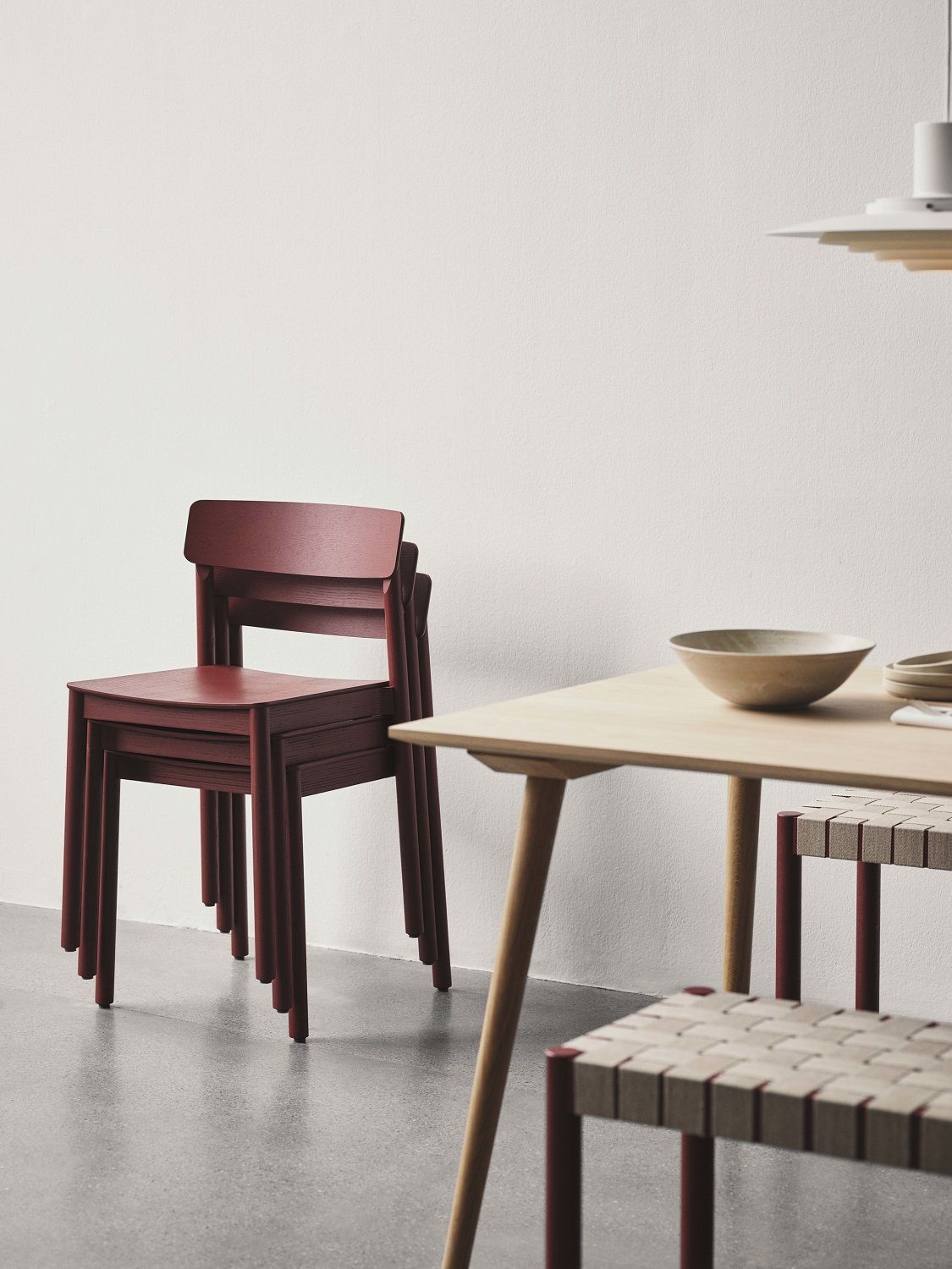 Gestapelte Betty TK2 Stühle von AndTradition in Burgunderrot, minimalistisches Design für Esszimmer und Wohnbereich.