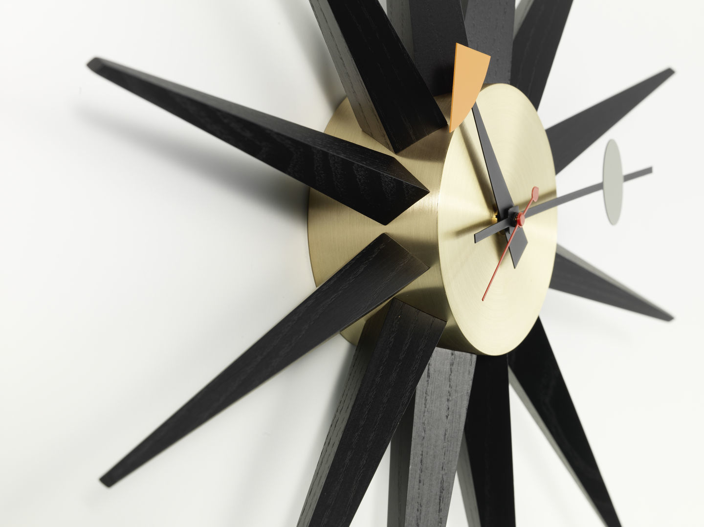 Nahaufnahme der Sunburst Clock Wanduhr von Vitra in Schwarz und Messing.