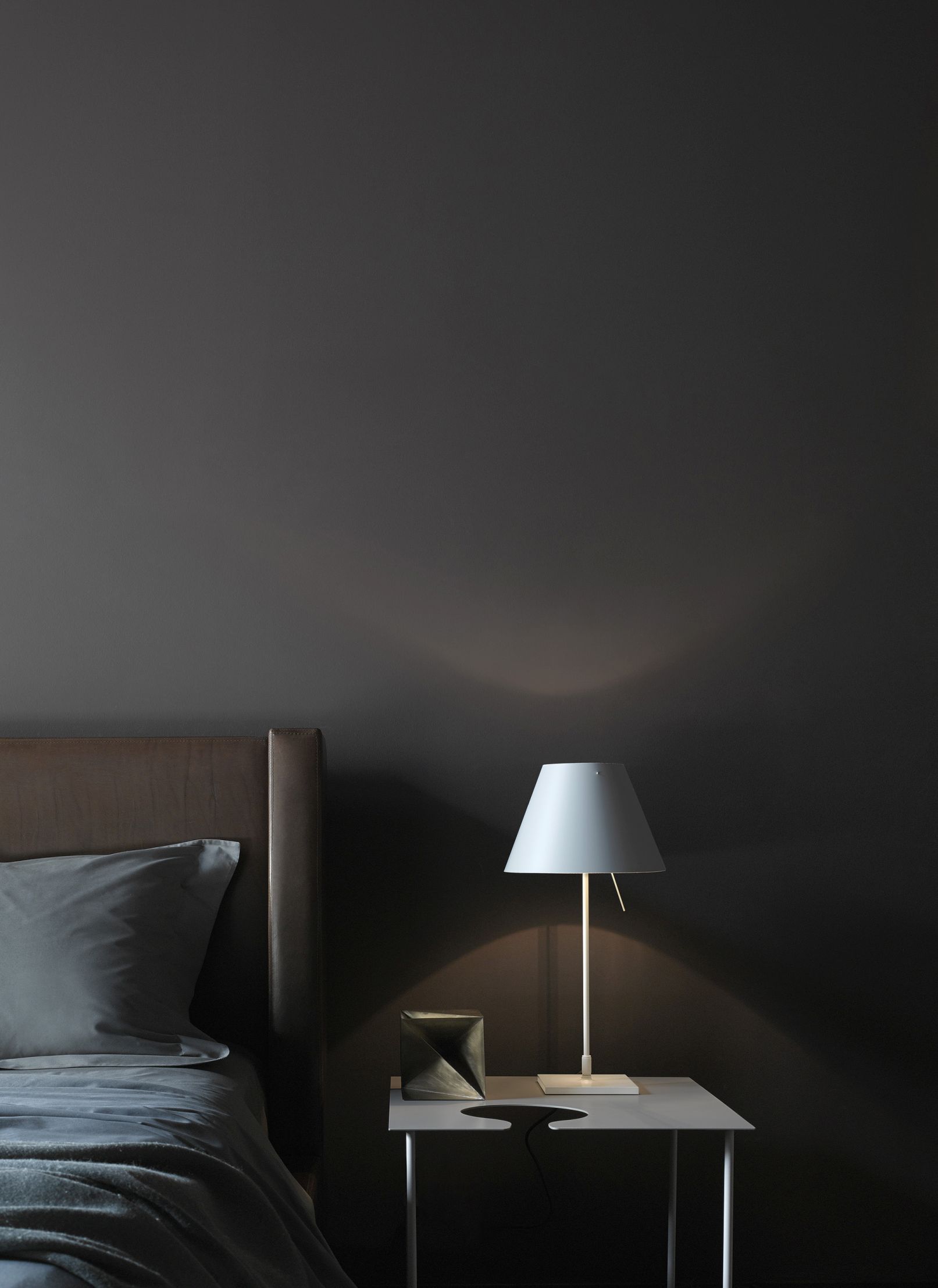 D13 Costanzina LED Tischleuchte von Luceplan mit Aluminiumgestell und weißem Lampenschirm auf Nachttisch.