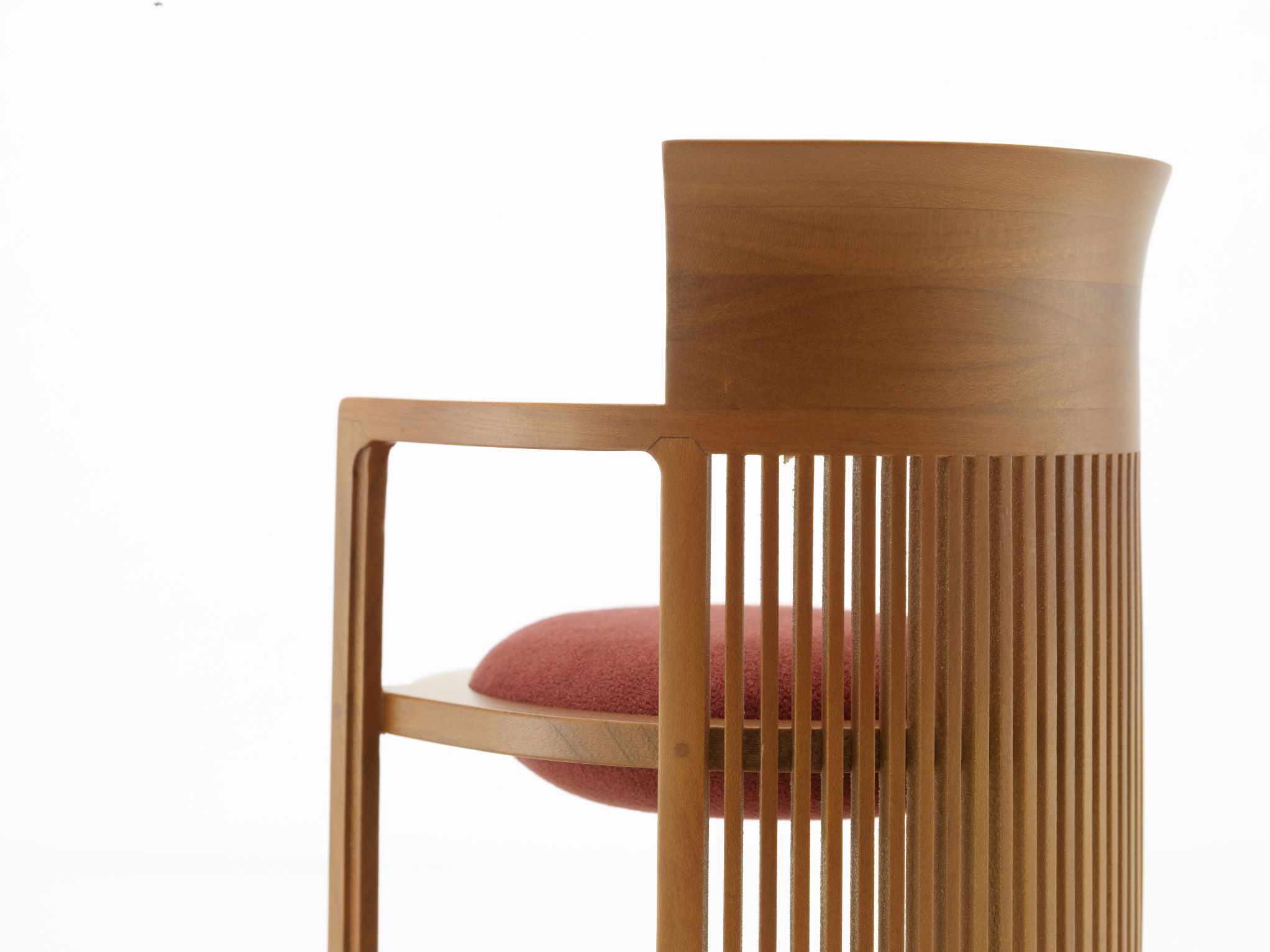 Detailaufnahme: Vitra Barrel Chair Miniatur Stuhl aus Holz mit rotem Sitzkissen.