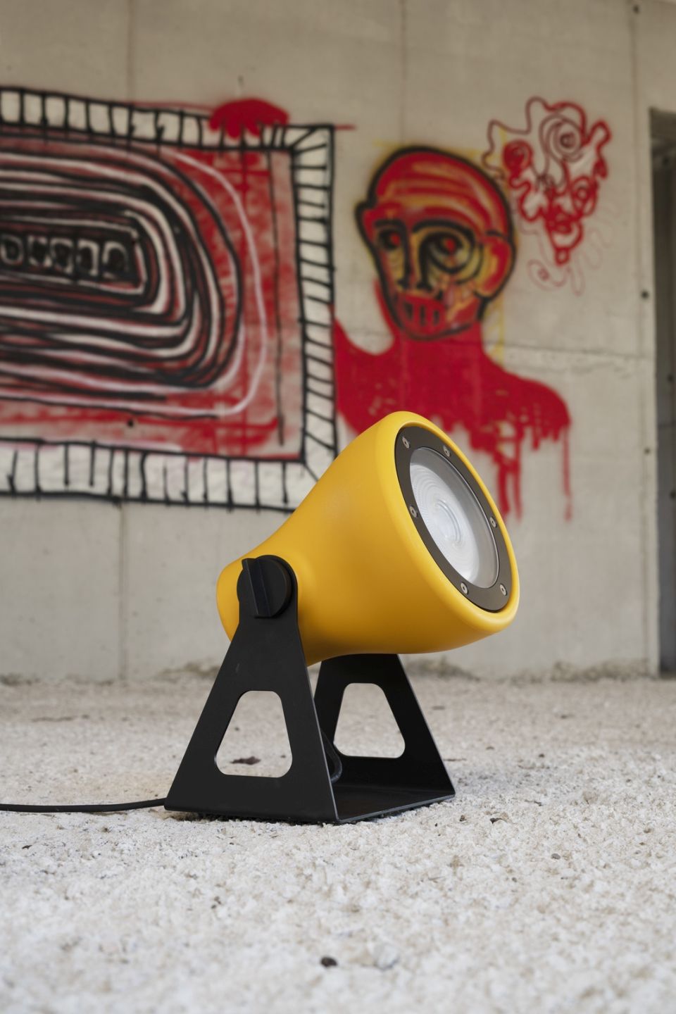 Orangefarbene Mini Frog Outdoor Leuchte von Martinelli Luce vor einer Betonwand mit Graffiti.