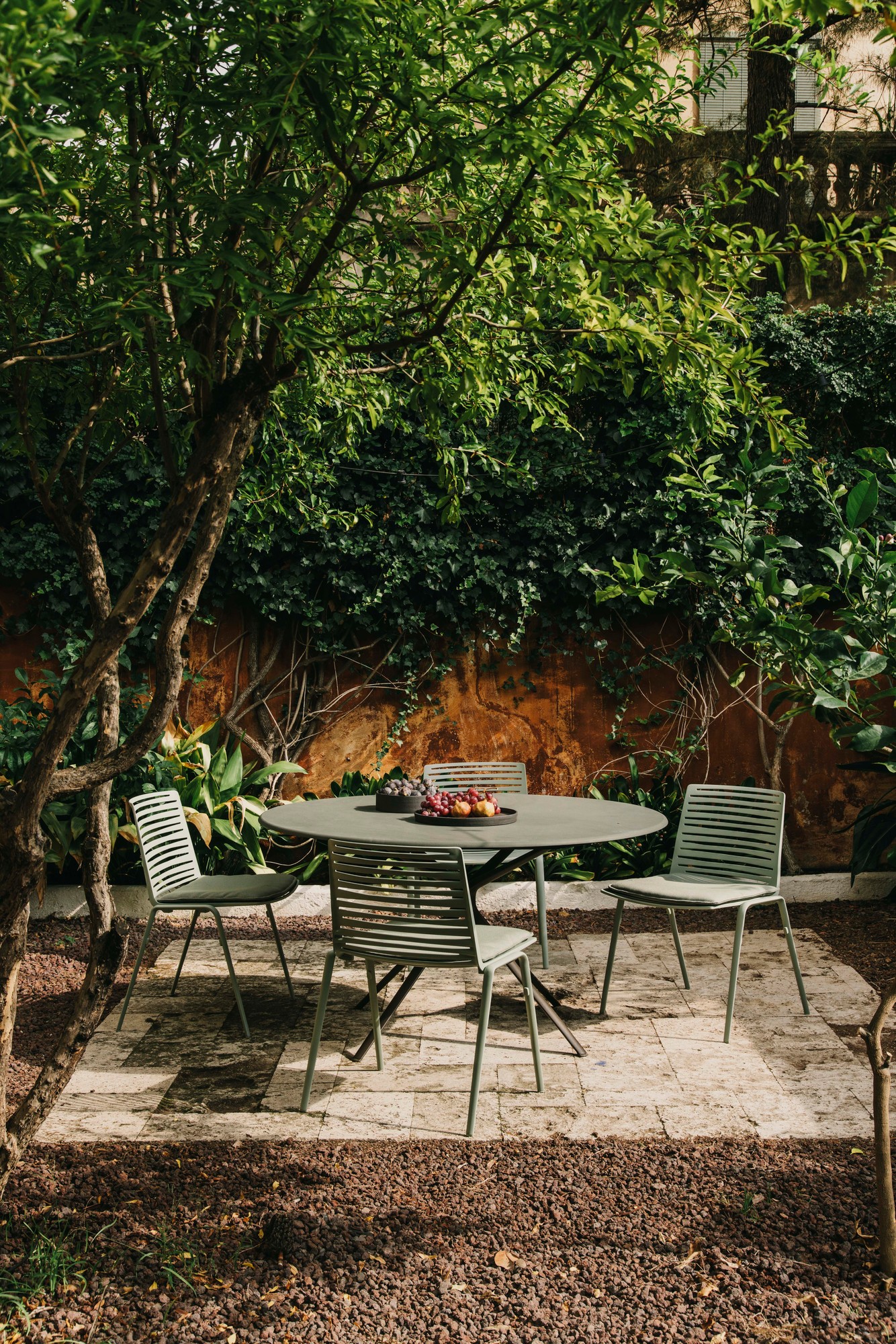 Zebra Outdoor Stühle Fast mit rundem Gartentisch auf einer Terrasse, umgeben von üppigem Grün.